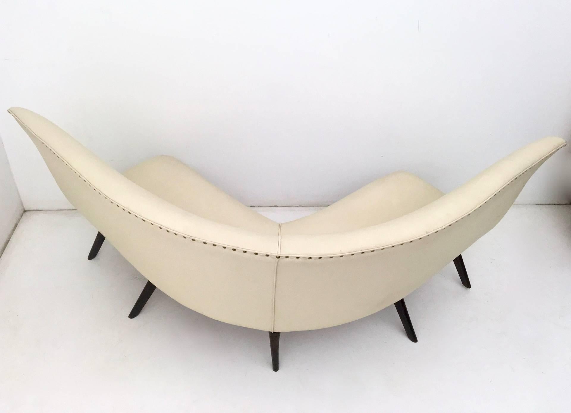Made in Italy, 1950s.
It features a wooden structure, which is padded and upholstered in ivory skai and brass details. 
This sofa is a vintage piece, therefore it might show slight traces of use, but it can be considered as in excellent original