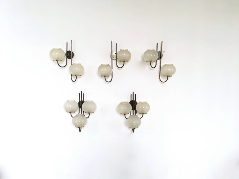 This is a set of three nickel-plated brass and frosted glass wall lights designed by Tito Agnoli and produced by O-Luce in 1961, Italy. 
These wall lights are vintage, therefore they might show slight traces of use, but they can be considered as in