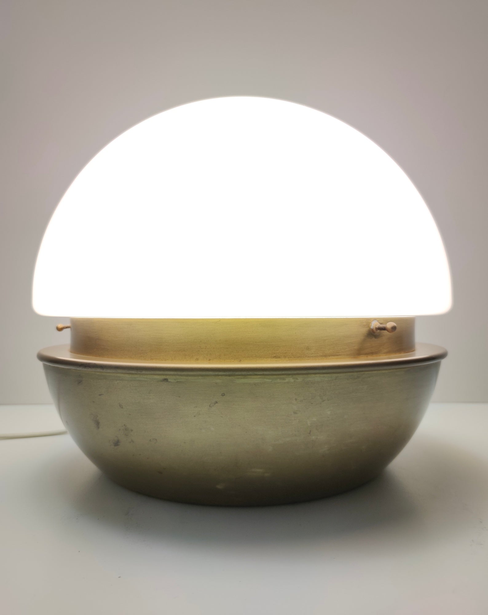 Fabriqué en Italie dans les années 1970-1980. 
Cette lampe de table est réalisée en verre Murano opalin, en laiton et en métal verni. 
Il s'agit d'une pièce vintage, qui peut donc présenter de légères traces d'utilisation comme on peut le voir sur
