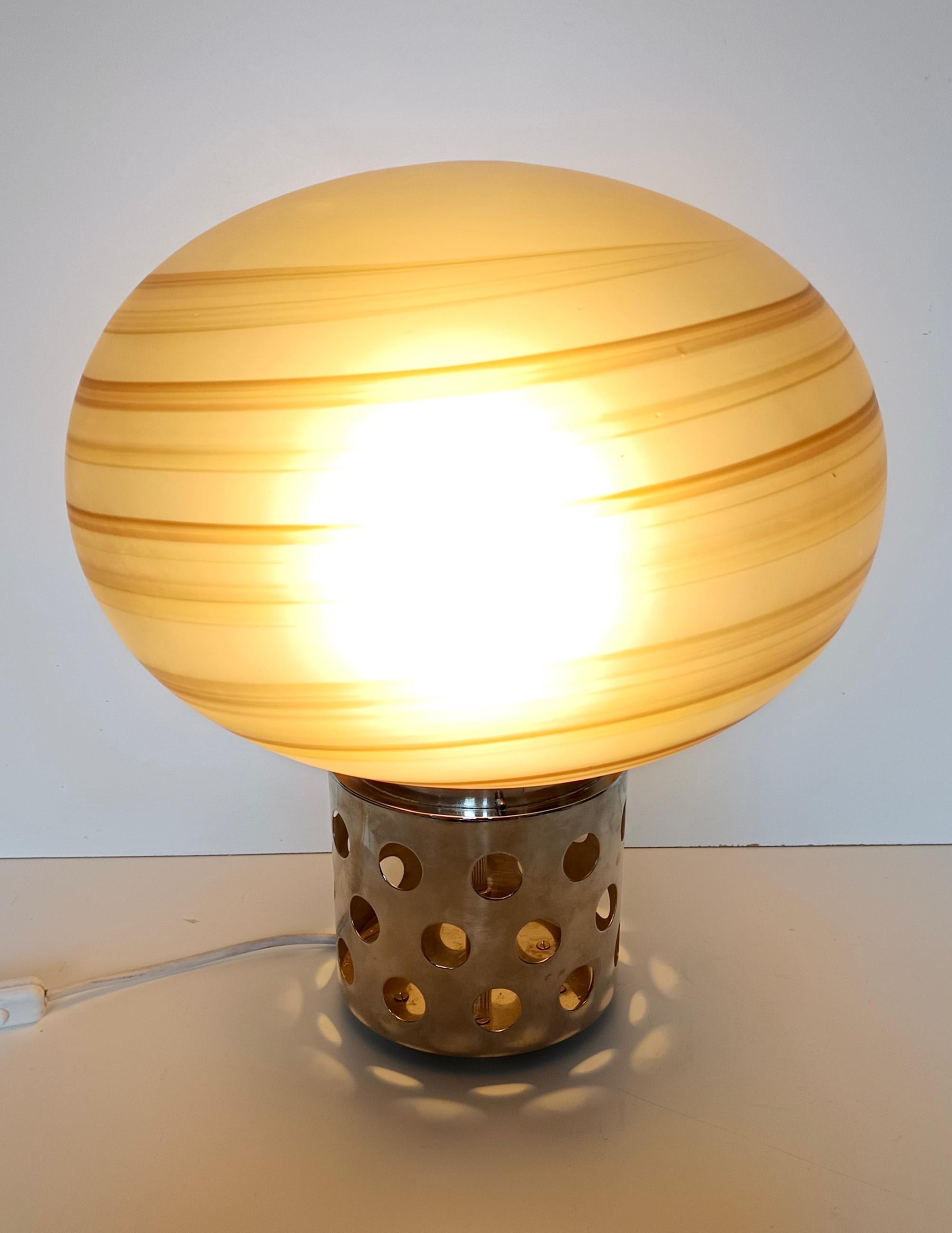 Fabriqué en Italie dans les années 1970. 
Elle se compose d'une base en métal chromé avec des trous et d'un abat-jour en verre soufflé brun et gravé. 
Il a été rénové et recâblé.
Il s'agit d'une pièce d'époque, qui peut donc présenter de légères