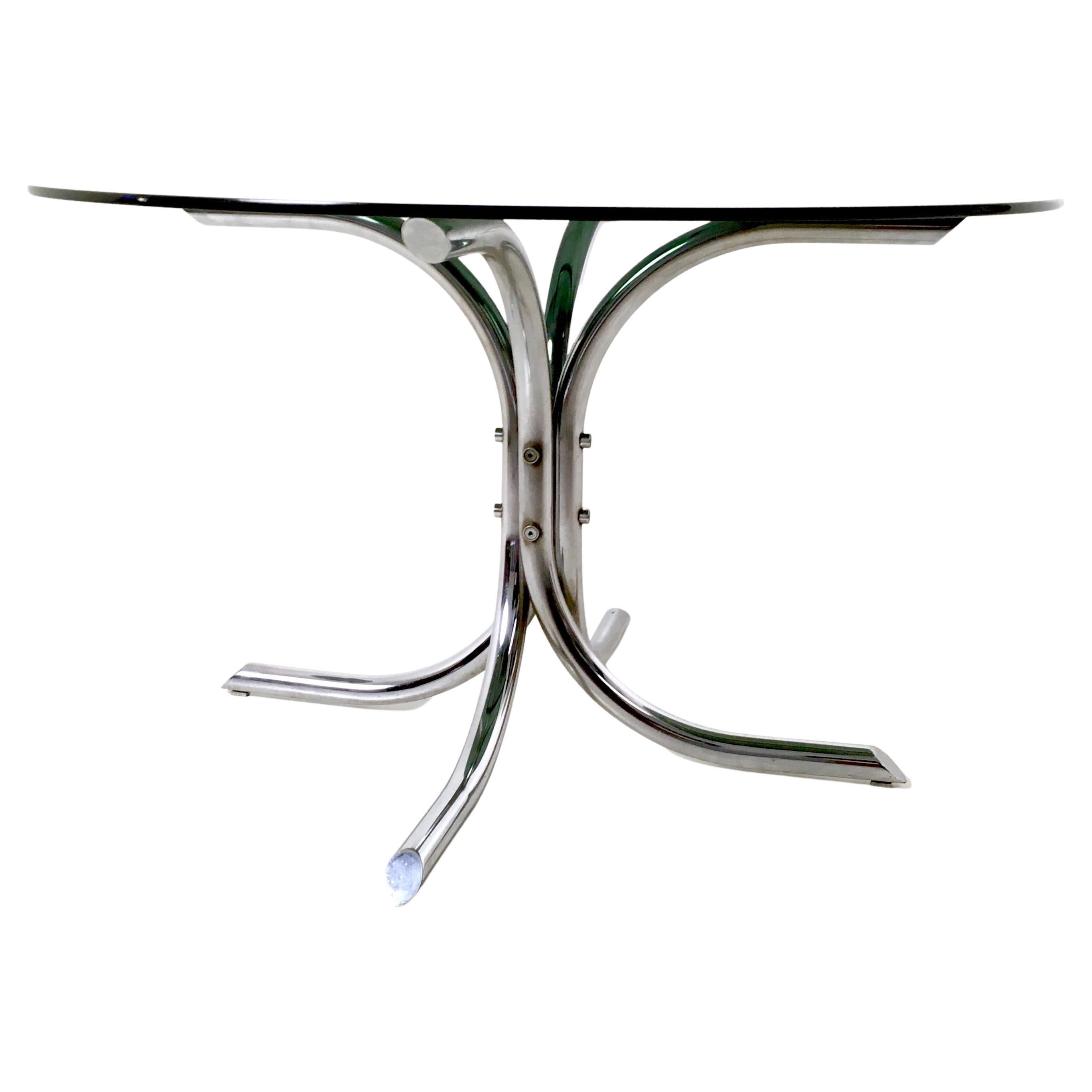 Italy, 1970s.
Designed by Studio Tetrarch and Produced by Bazzani.
This table features a round smoked glass top and a chrome-plated metal pedestal. 
It is a vintage piece, therefore it might show slight traces of use, but it can be considered as in