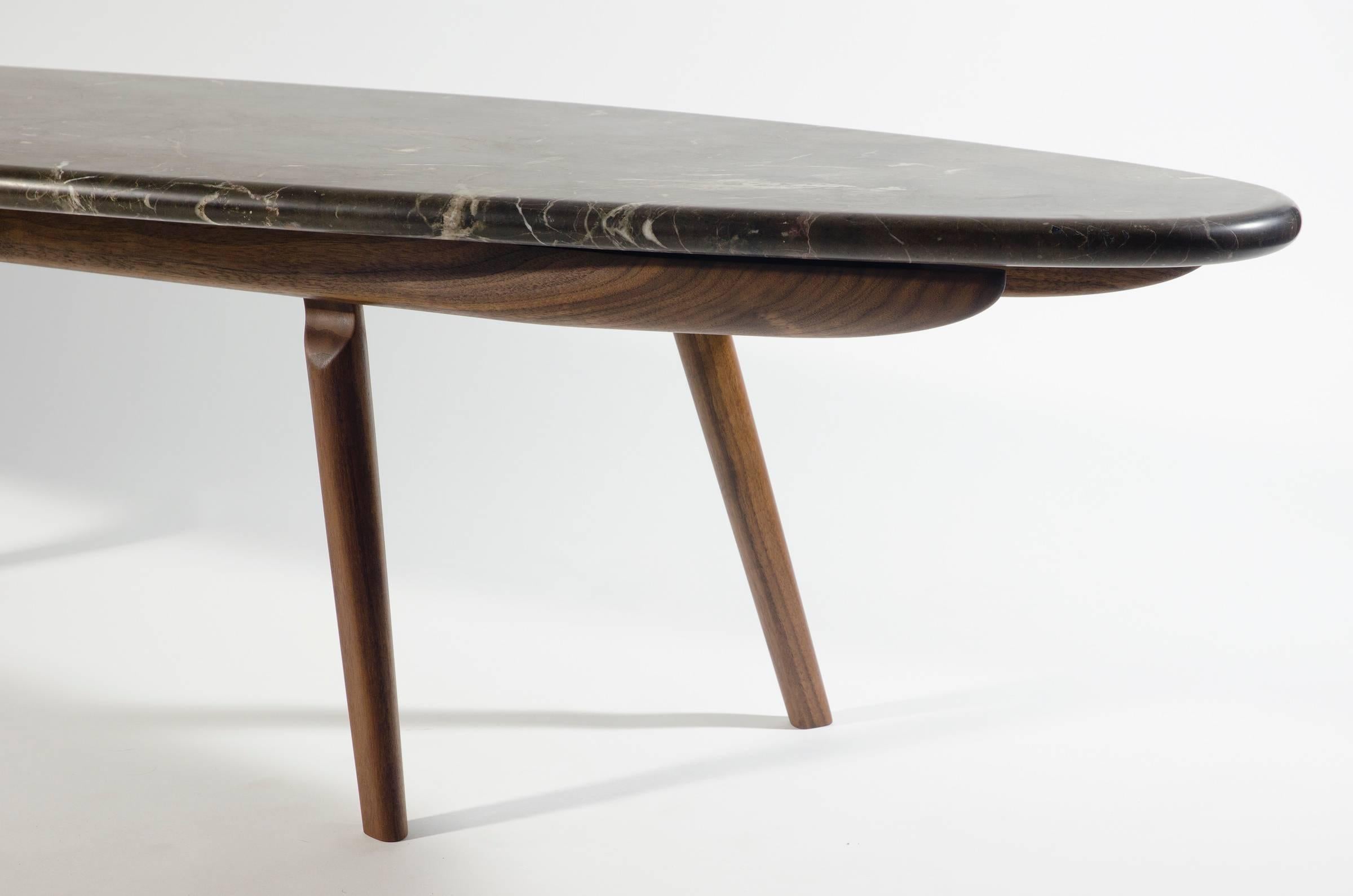 In a similar spirit to the skip table, the Wendel table's form is inspired by hydrodynamics. Like a large stone in a moving body of water, the Wendel Table holds its place in any setting. The honed black marble and oiled walnut give a strong