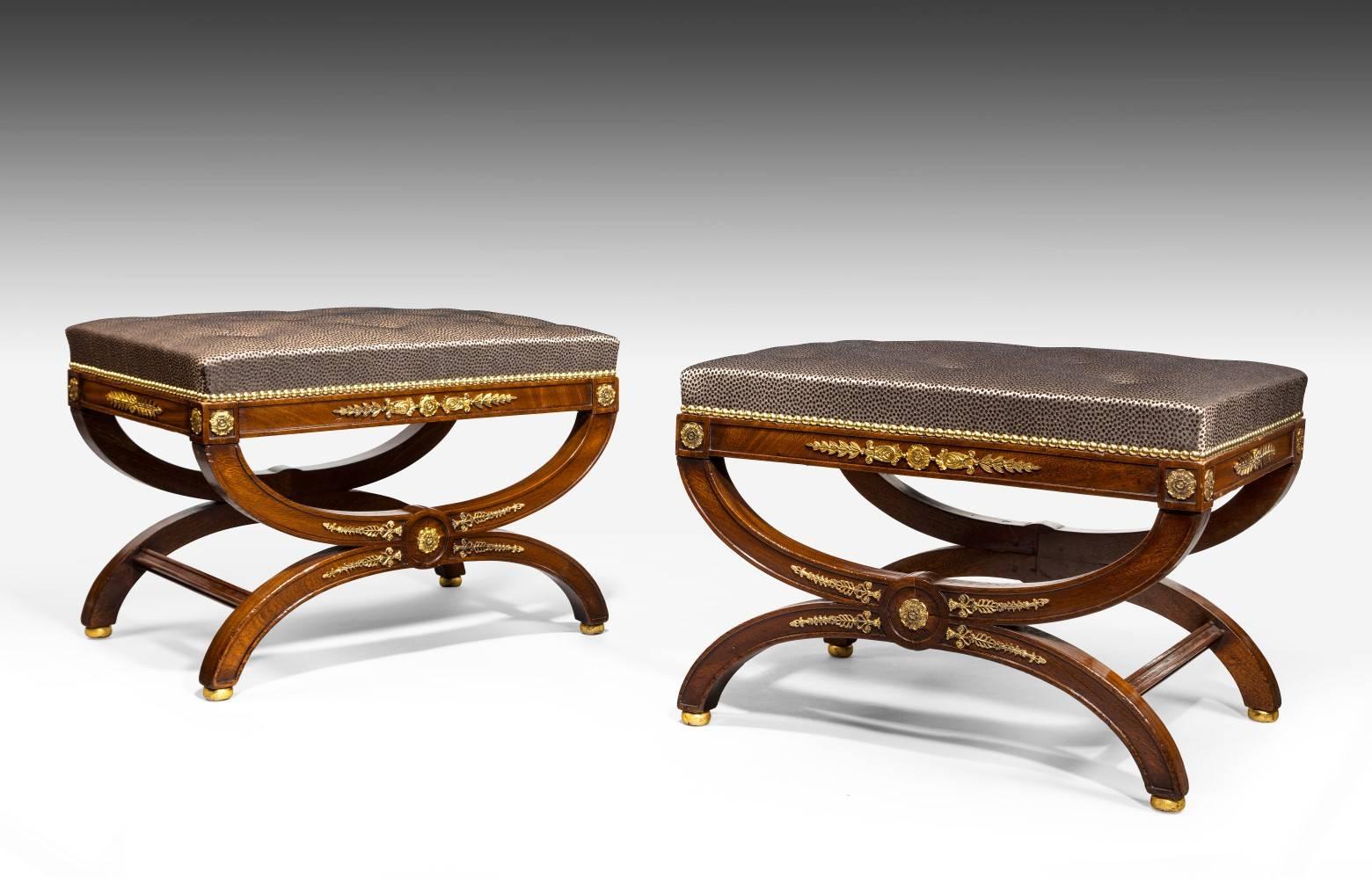 A pair of 19th century French mahogany and ormolu stools. Of a generous size and good quality, these stools have applied ormolu mounts on both sides. They have recently been upholstered using traditional materials and techniques and are of a good