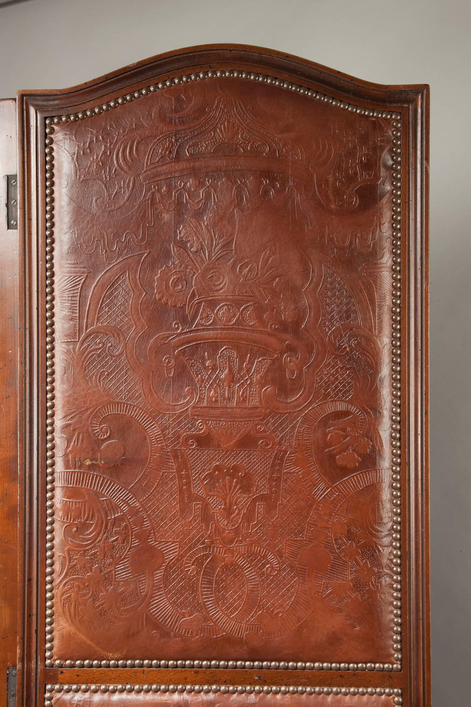 This screen retains the original embossed leather panels that are inset to mahogany moulded frames. The leather is a good color and bordered with brass studs. The condition of the screen is good and this screen can be used as either floor standing