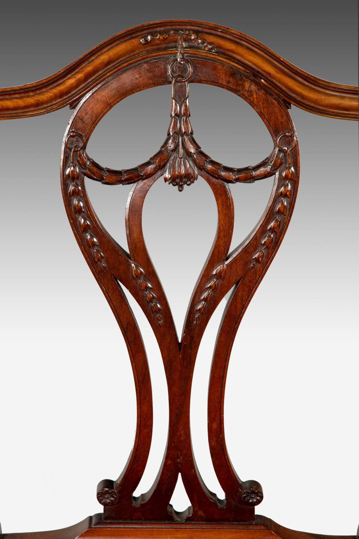 Made from Cuban mahogany, these chairs have shaped backs with a central pierced splat that is decorated with good carved decoration. The stuff over upholstered seats with a serpentine front rail and the front legs have an unusual splay at the