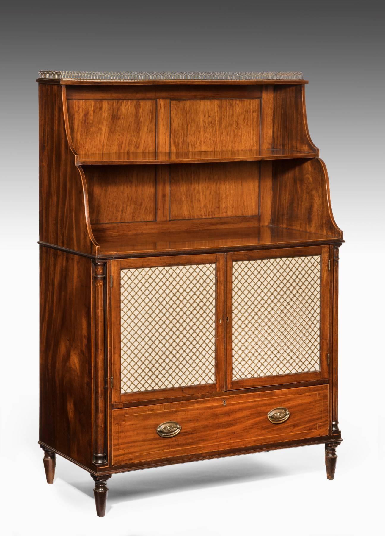 Made from Cuban mahogany, the bookcase is of excellent color. It has a brass gallery above graduating shelves and the base has a cupboard with twin doors that have inset grills. It also has a long base drawer and the excellent quality of the