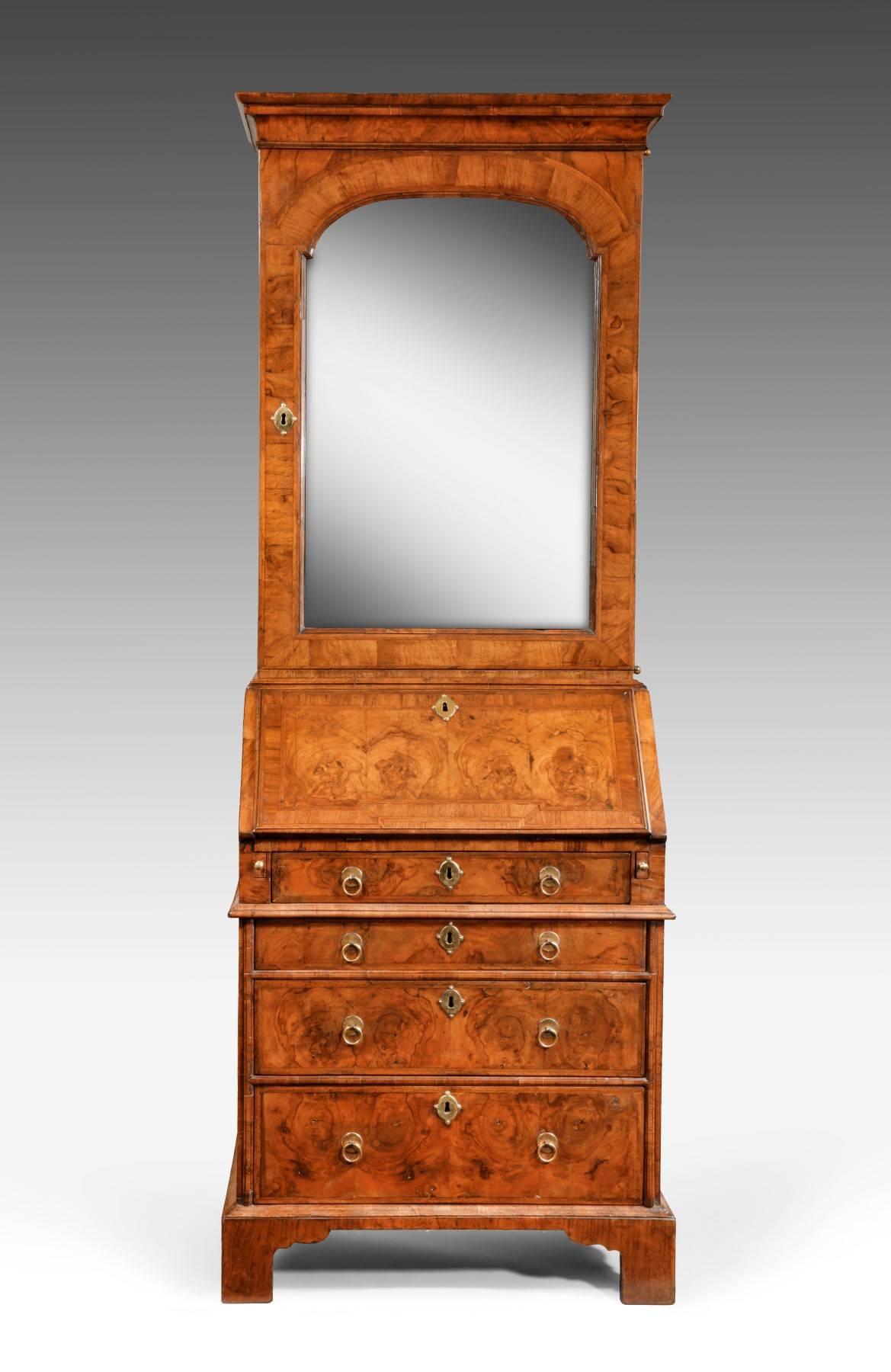 This rare bookcase dating from the early 18th century is veneered in figured walnut. It has cross grain mouldings throughout including a shaped waist moulding and both the top and bottom have herringbone inlay as well as cross banding decoration.