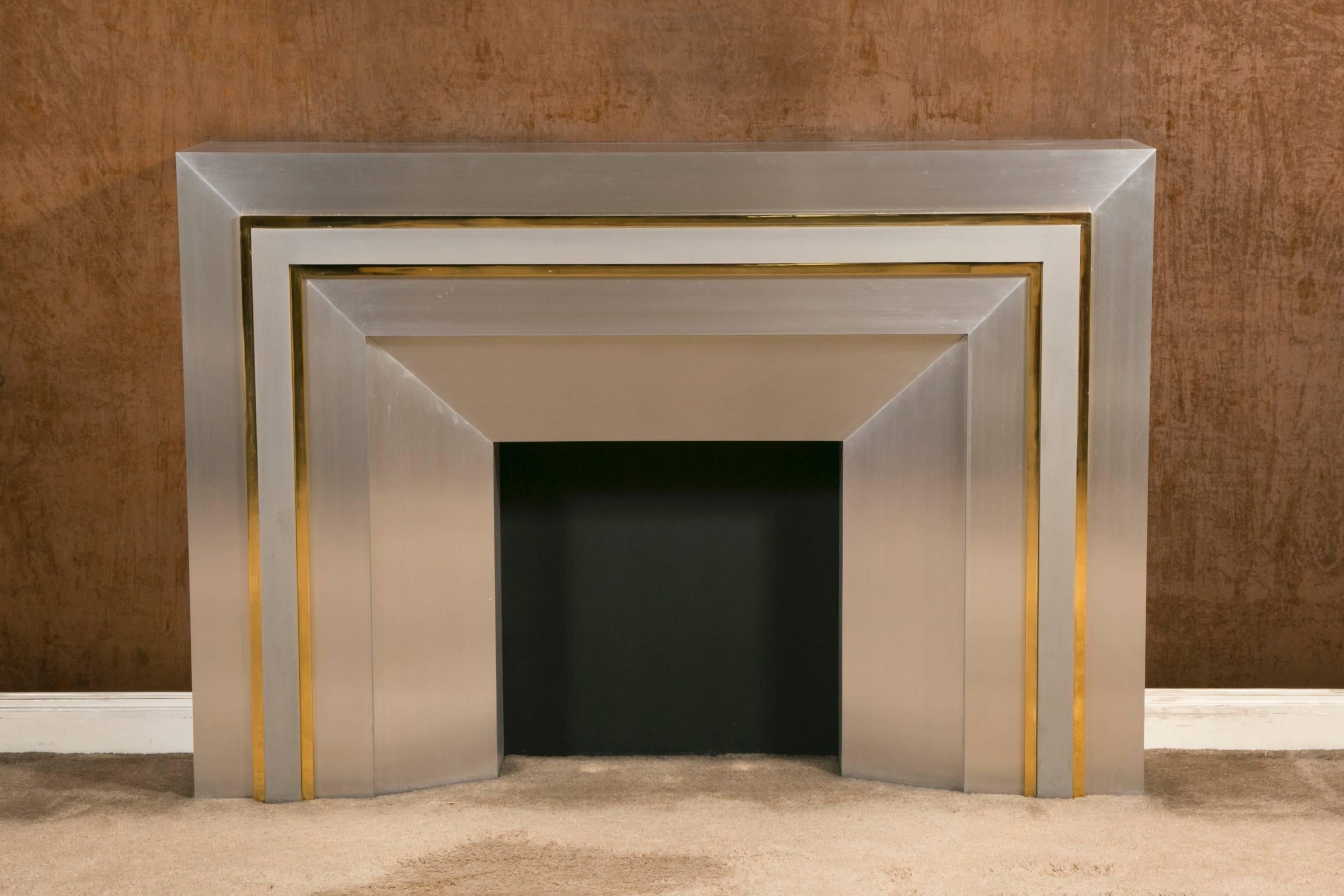 Large decorative modern fire mantel, with a brushed aluminium finish and polished brass frames.