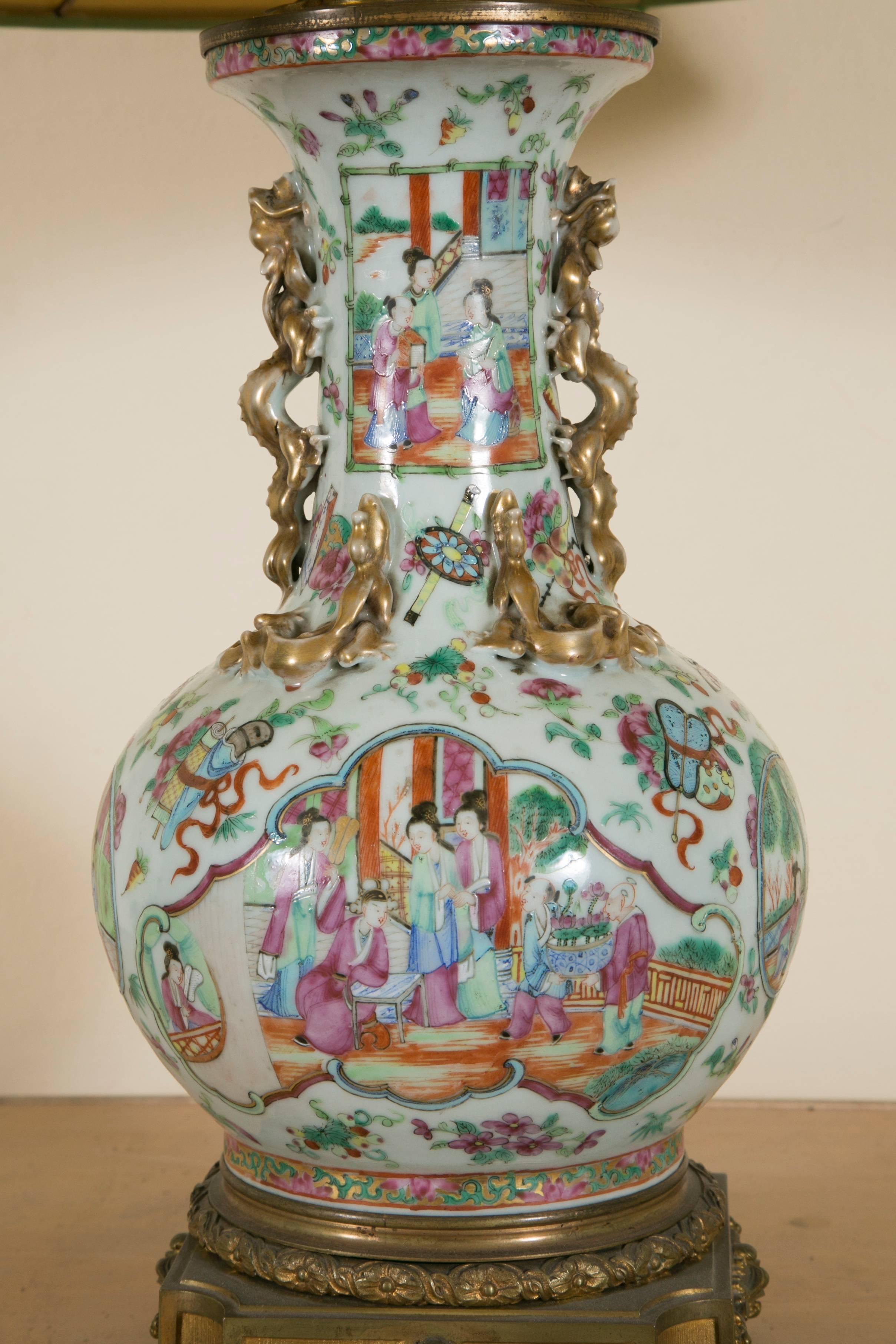 19th polychromed enameled Chinese porcelain lamp base mounted on a LXVI style finely chassed gilt bronze base and top,
decorated with rubans, floral wreatht, roses, buterflys, fruits and musical instruments, depicting joyous scenes in a garden with