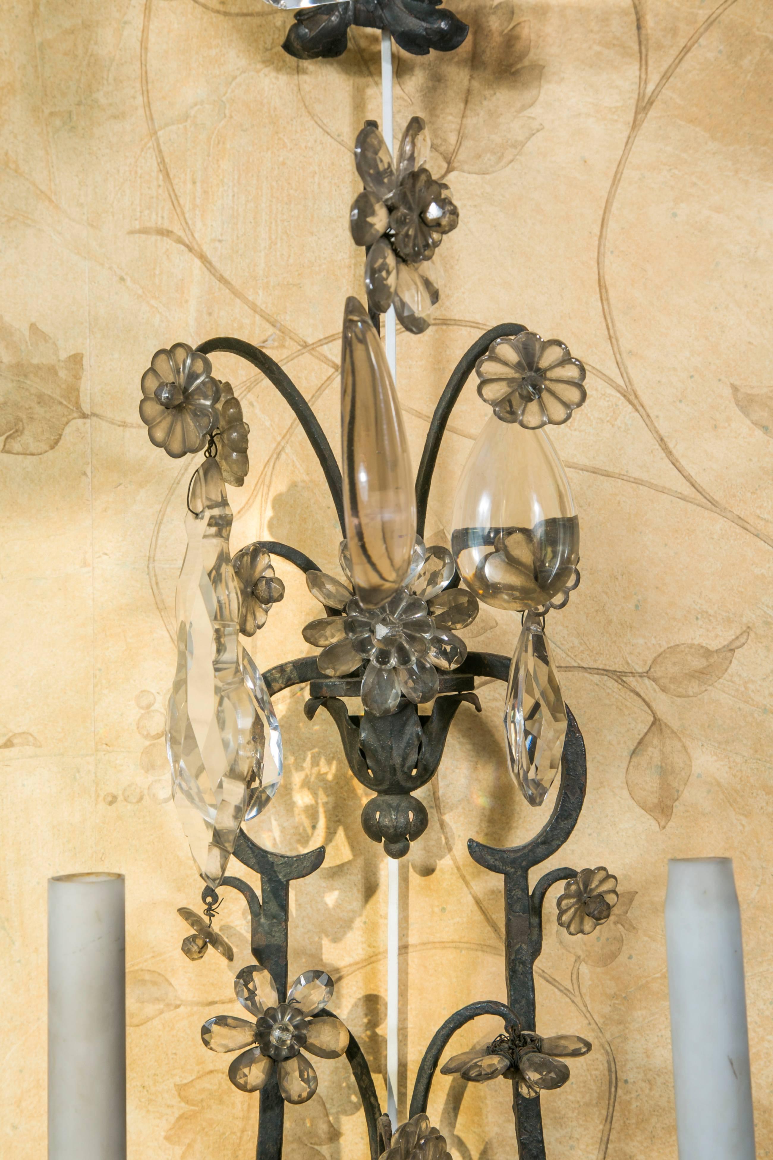 Pair of patinated black iron wall sconces, five arms, with white, smoke and amethyst color crystal droplets.
In the manner of Maison Baguès

Wired to EU standard.