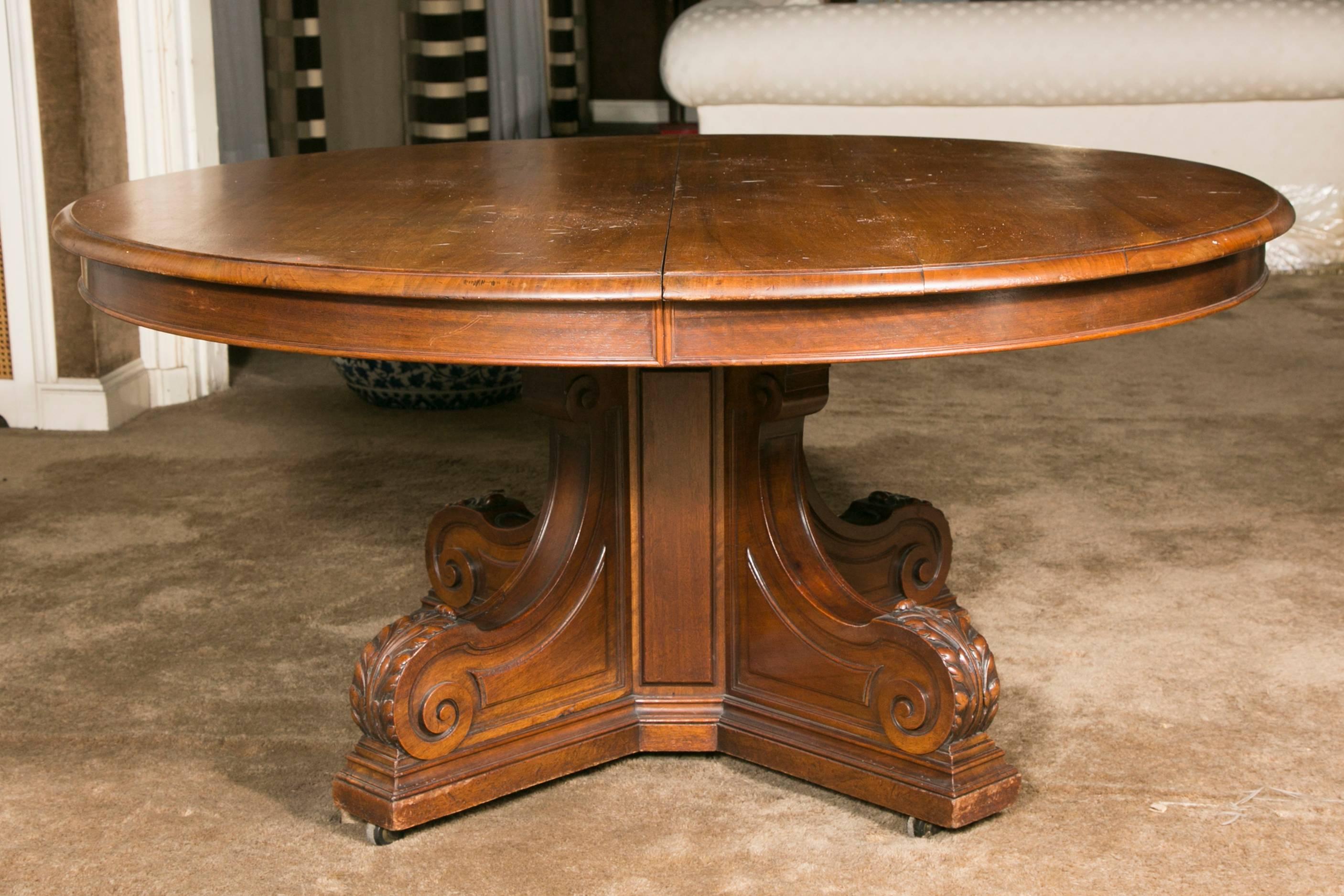Large round extending dinning room solid walnut table on a center feet with acanthus leaves, possibility to extend it with four extensions that must be made by the customer,
when open, two fluted extra legs come down to give stability to the table.