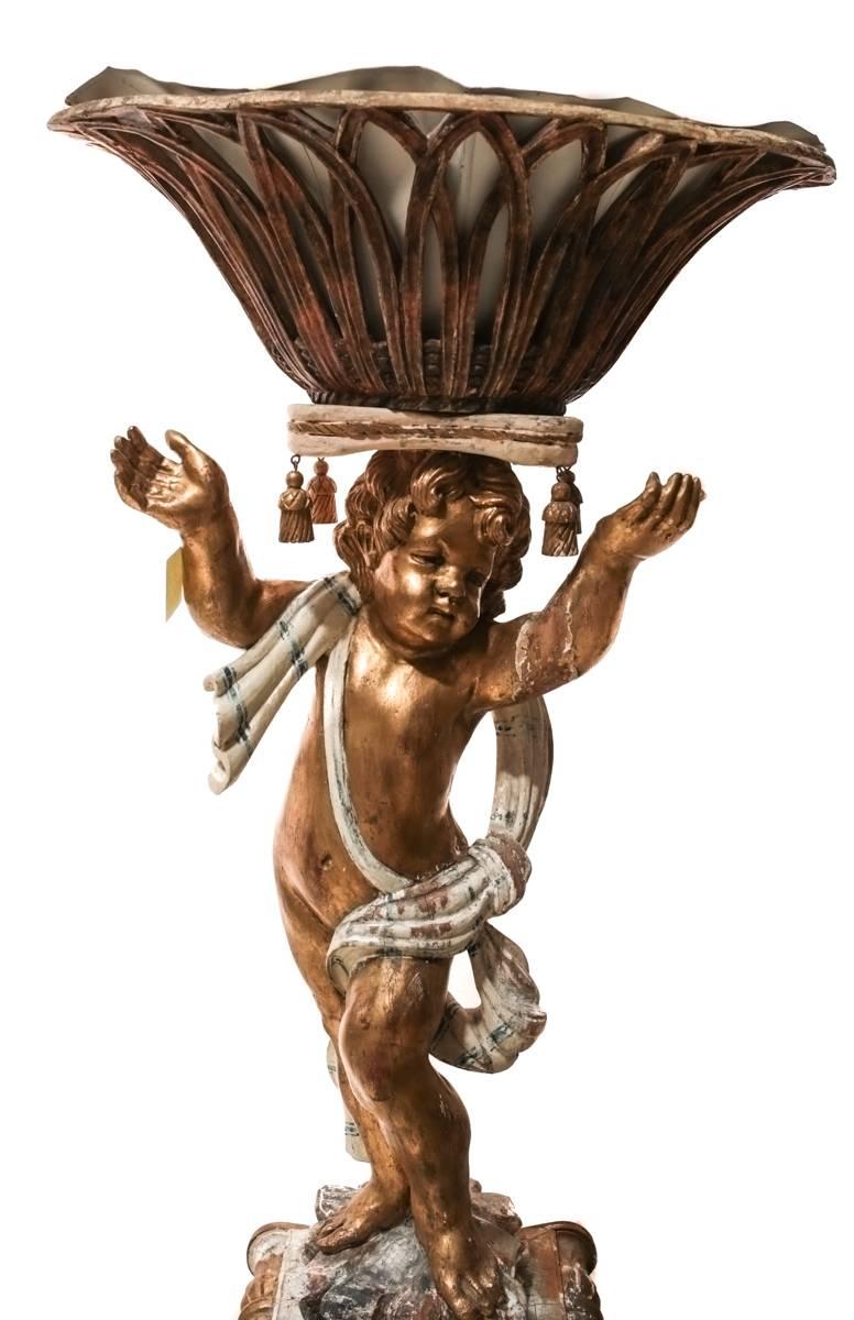 An exceptional pair of figural planters from Italy, likely dating to the second half of the 18th century. Each column is finely hand-carved and gesso and gilt painted depicting a charming putti with free flowing garbs elevating a basket formed