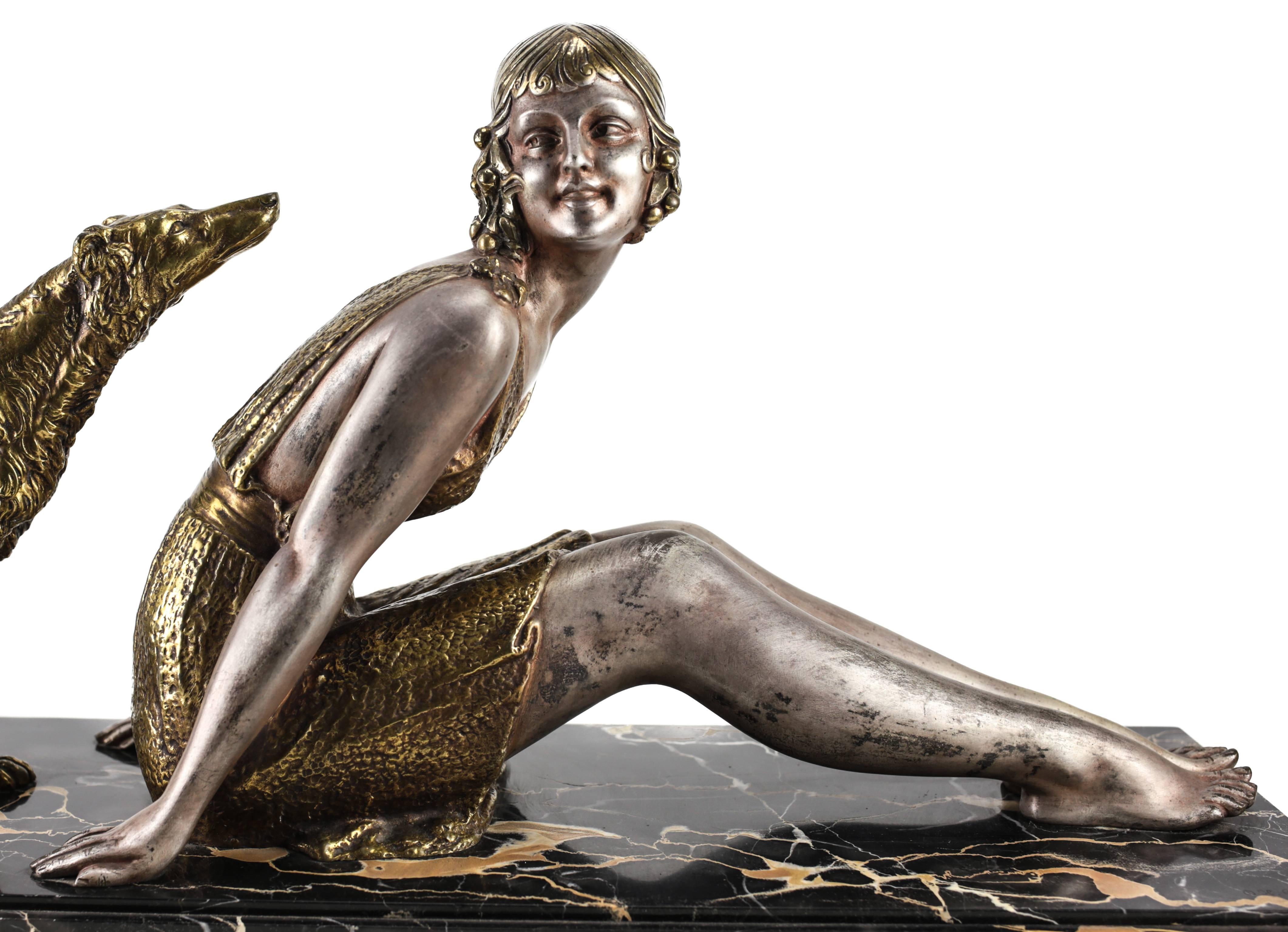 An attractive Art Deco silver patinated and gilt bronze sculpture of a seated woman, embodying a flapper, cheerfully posing with her endearing borzoi dog, mounted on a portor marble base. Inscribed foundry mark for 
