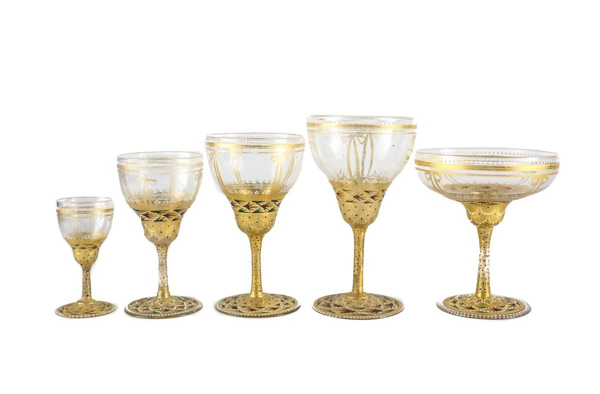 With elaborate gilt and jeweled enamel decor, an extensive Italian stemware service including three serving decanters, eight of each water, wine, champagne, claret and aperitif, along with a matching dessert service consisting eight of each berry