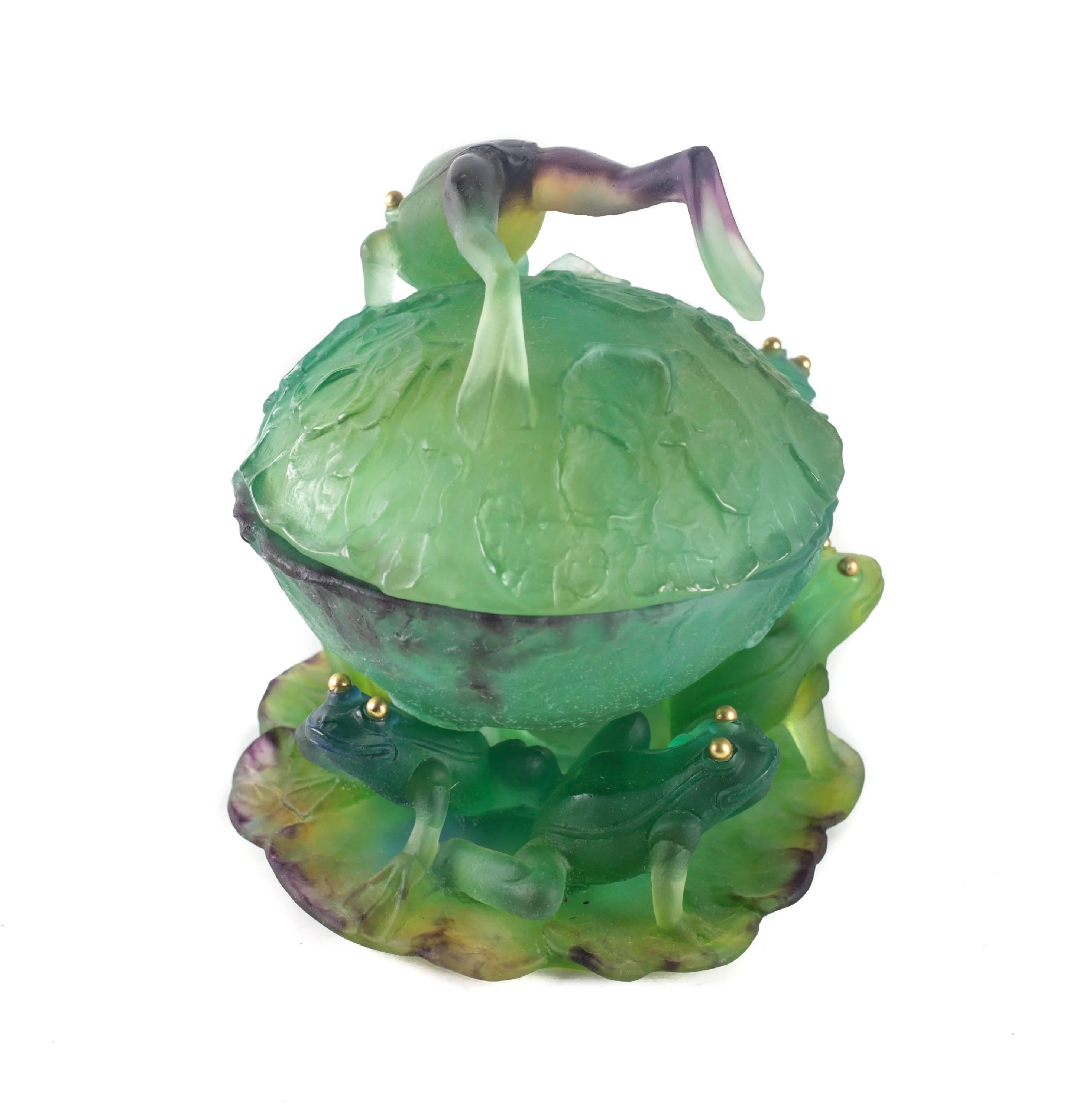 A delightfully creative, bright and colorful art glass lidded bowl created using pâte de verre (moulded within a kiln) technique. Five frogs set atop a lily pad to the foot of the bowl with a leaping frog serving as the handle to the lid, all with