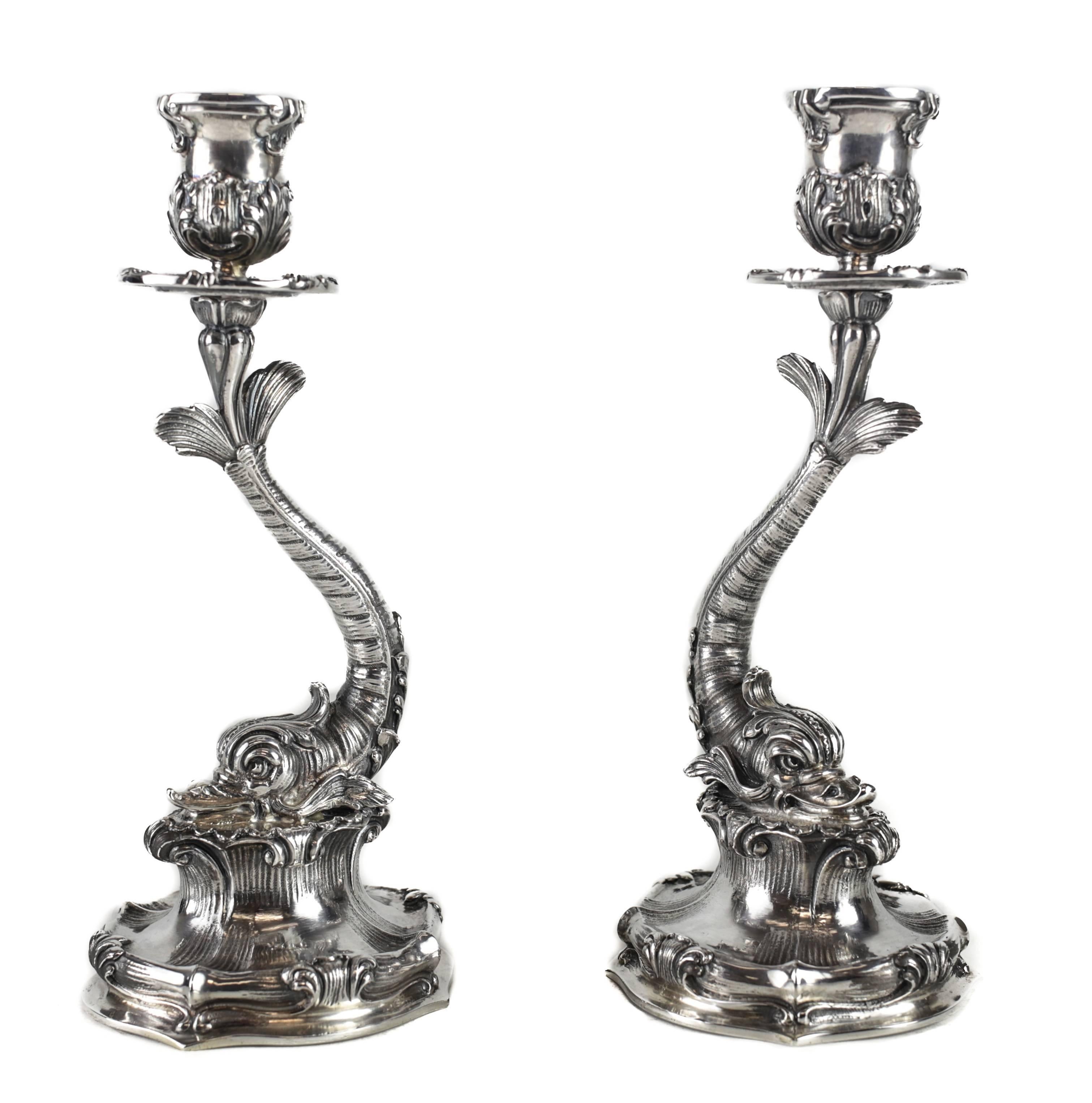 A striking pair of sterling silver candlesticks retailed by Buccellati Italy, each modeled in the form of classical Italian dolphin, perched on a bed emitting waves, accented with Baroque inspired crests. From the workshop of master silversmith