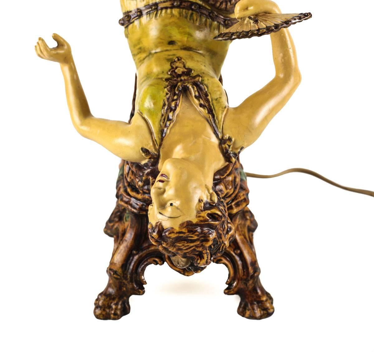 An attractive polychrome decorated cast metal lamp taking the form of a 1920s burlesque entertainer. The young beauty portrayed with bobbed hair, beaded waistband, fan and ankle laced flats as she balances the colorful glass shade, constructed in