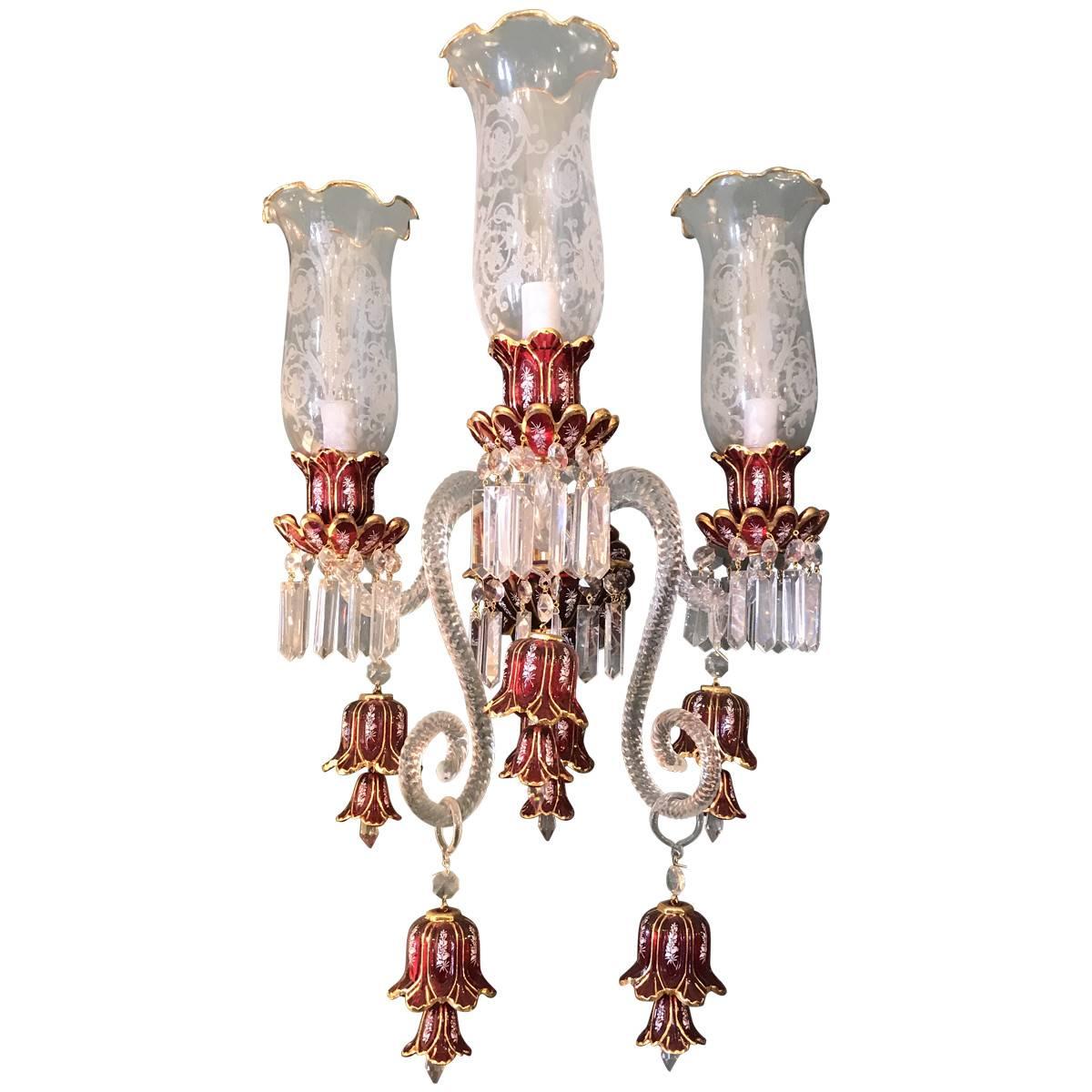 Midcentury Baccarat style Bohemian ruby glass sconces with hand-etchings, cranberry touches for accent, and three arm lights with etched bulbs, these opulent wall sconces make a striking statement. They are designed in a traditional style with