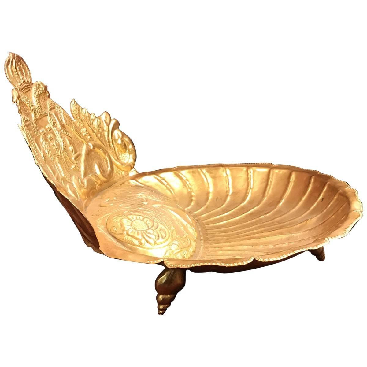 Gleaming from its gilded surface, this vintage dish is ornately decorated with a shell design and detailed armorial with a double-headed eagle and shield. Delicately supported by shell feet, this piece adds a luxurious touch.
