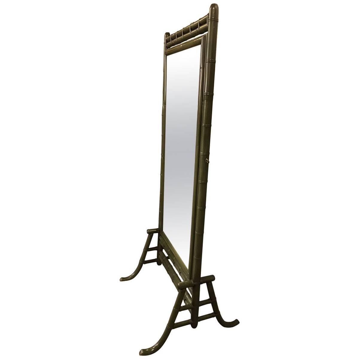 Designed in the Hollywood Regency style with its signature touches of the global inspiration, this vintage floor mirror has a dark green hardwood frame carved to resemble authentic bamboo. Made during the 1960s, this piece pivots to make getting