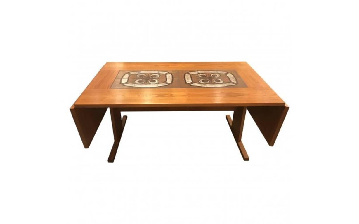 A midcentury Gangso Mobler was a leader in modern Danish design with a reputation for crafting exquisite pieces in natural materials, such as warm hardwood. This drop-leaf teak dining table has small panels inlaid with handmade ceramic tiles for an