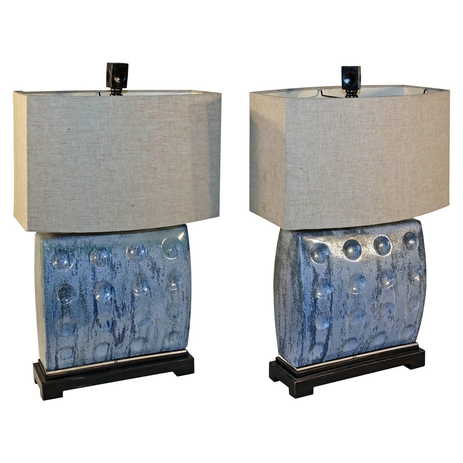 This amazing pair of Mid-Century glazed studio pottery mounted lamps are in excellent used condition. They are mounted on a Lucite wooden base and are topped with attractive wooden finials over a linen shades.

The lamps measure 5" deep x
