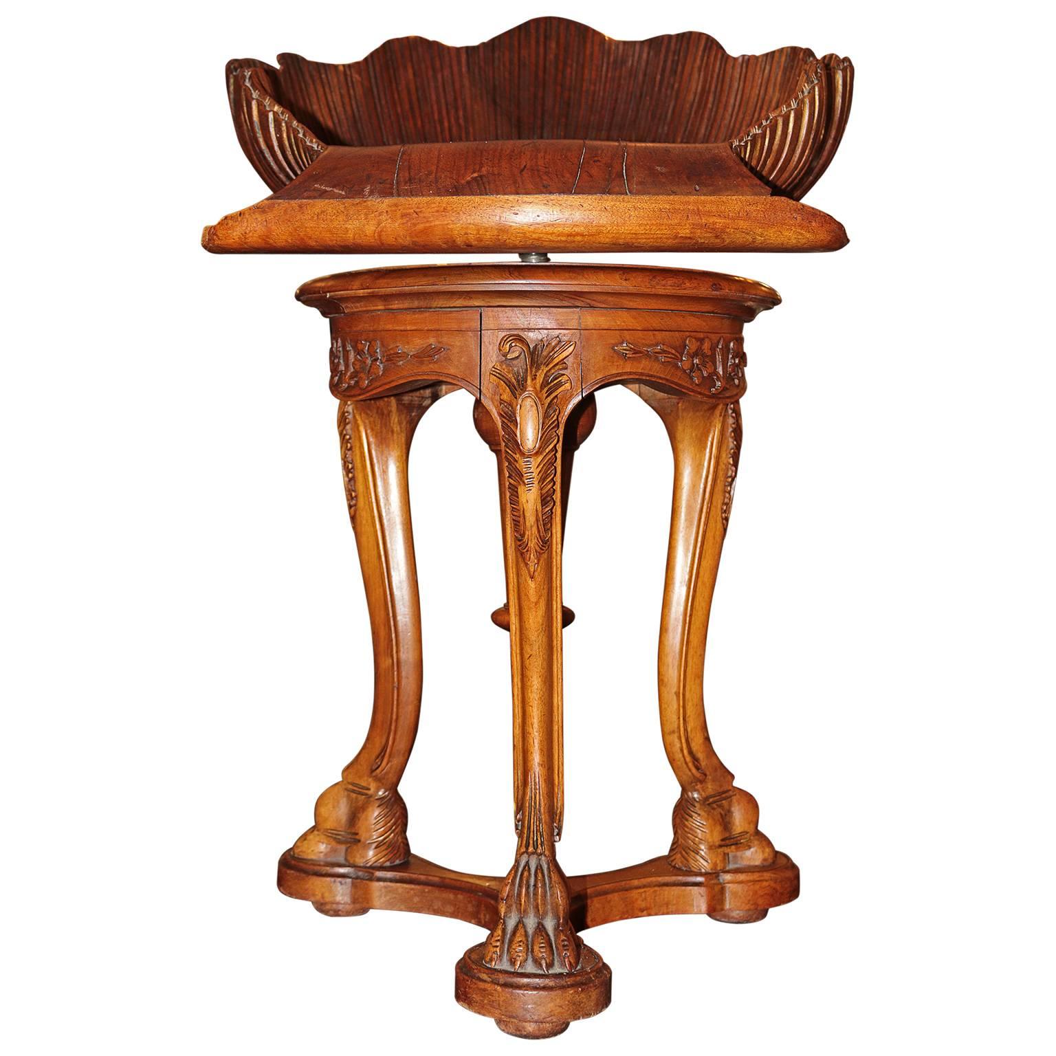 Adjustable early 20th century finely manufactured rocaille shell seat swivel stool has a metal rod connecting the base to the seat with tripod connecting legs. This swivel seat at its lowest height is 19
