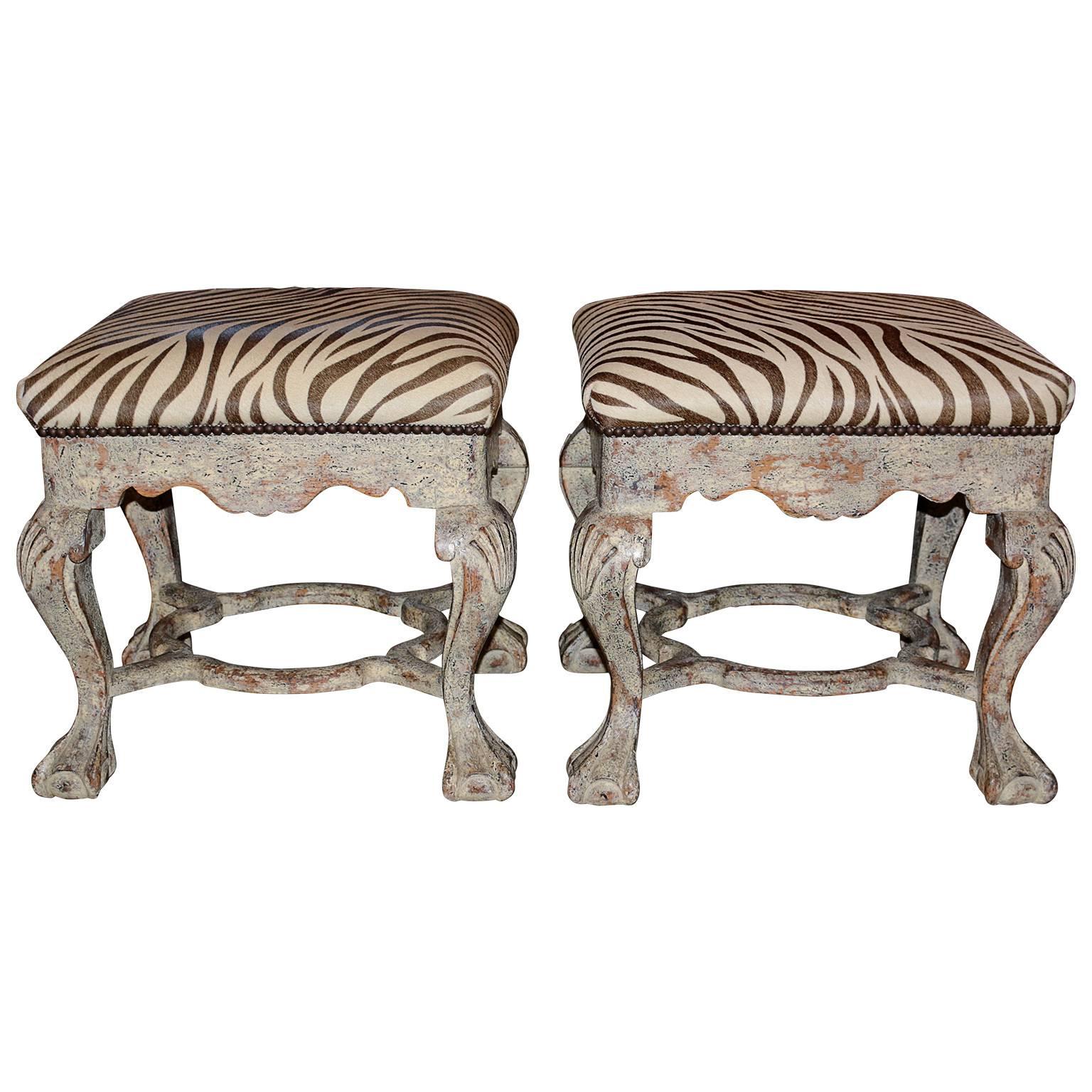 Pair of hand-carved Itaian zebra printed cow hide foot stools. The cowhide zebra print is in great condition being held by nailheads. The hand-carved leg have a carved in clam shell with eagle ball foot at the base. 

Contact us for an accurate