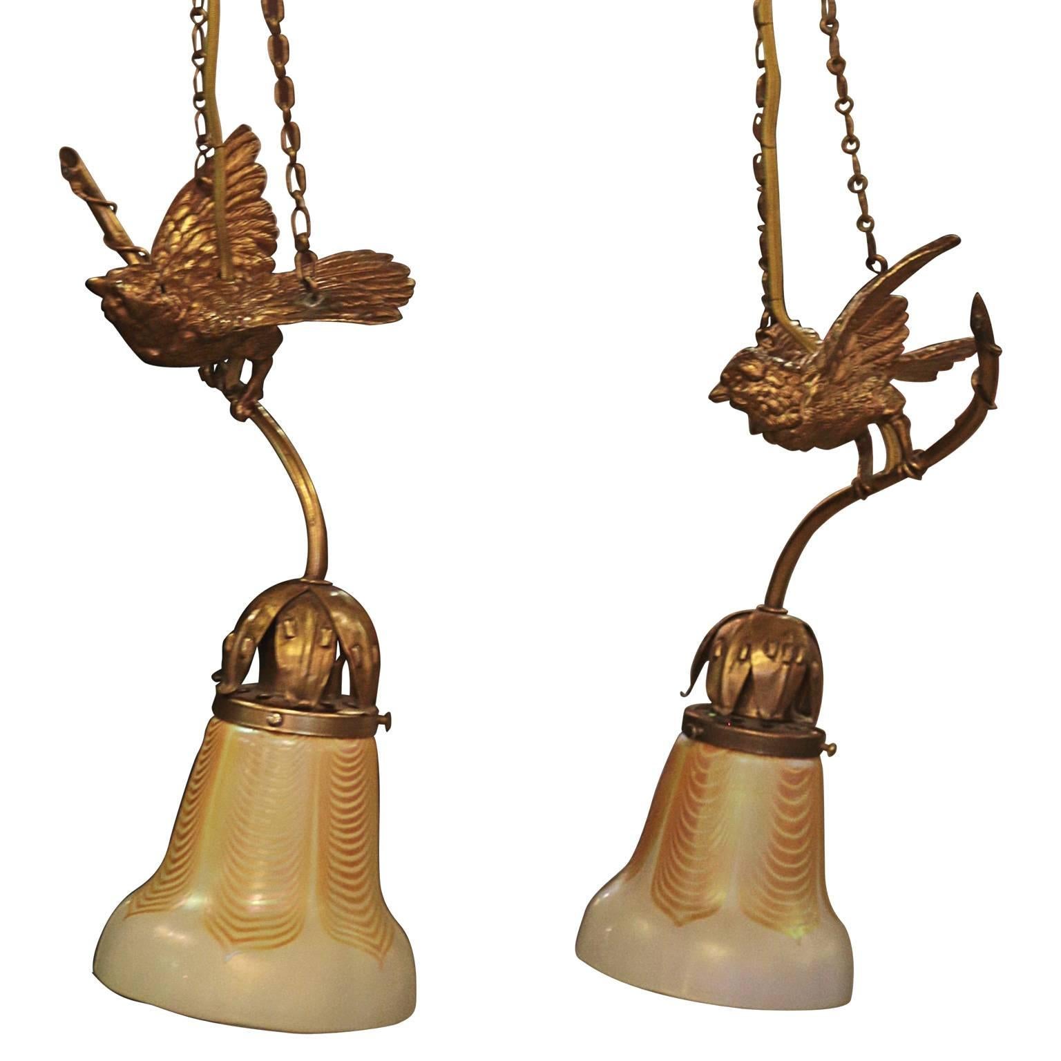 This great pair ormolu hanging lights with Steuben shades are in amazing used condition. The form of the birds is excellent and proportioned. The lights hang from a chain connected to any form of hook that a chain may fit. The wire follows the chain