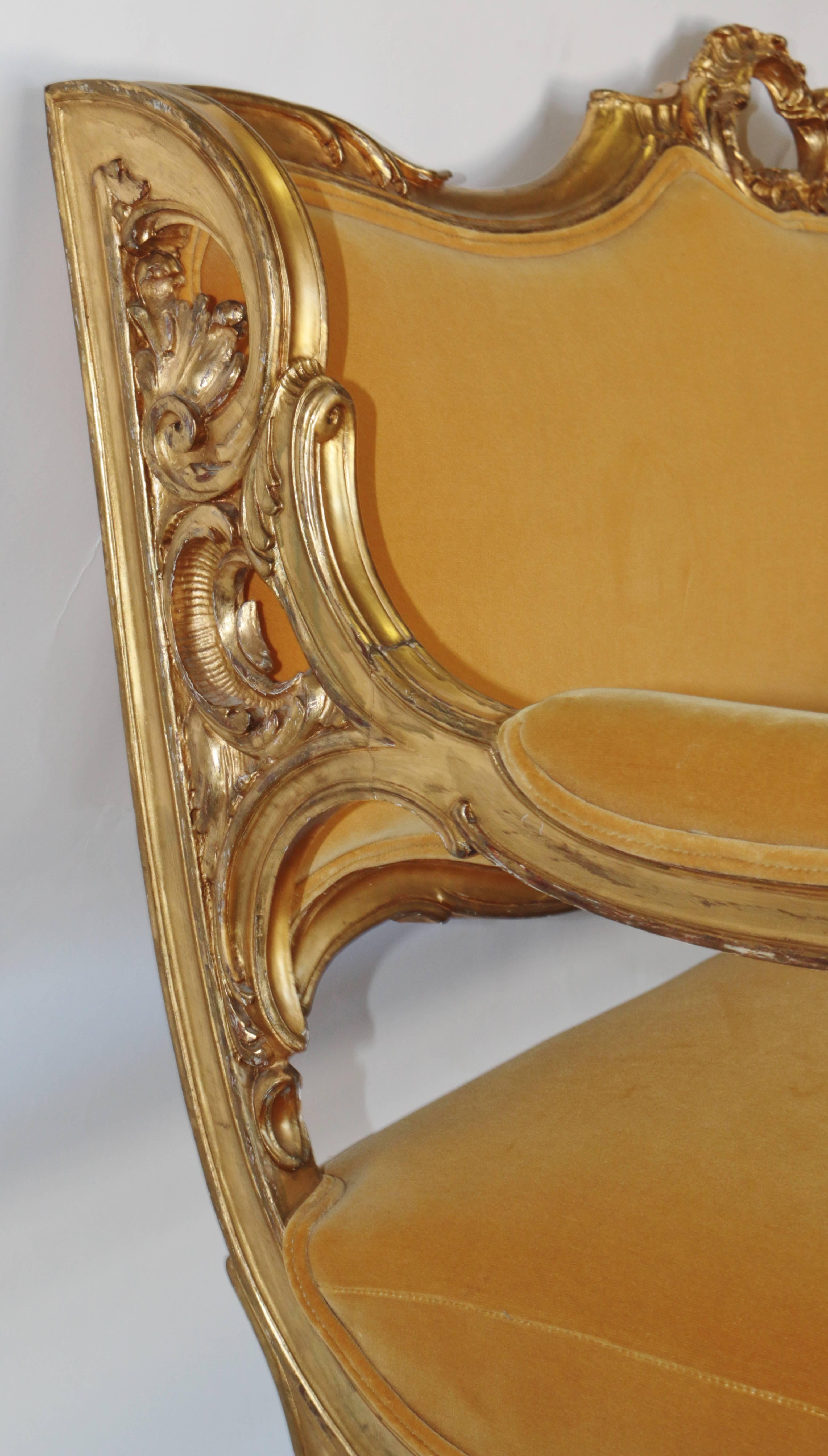 Beautiful settee in a handsome yellow velvet with original giltwood frame. The Velvet is reupholstered. The original giltwood frame is untouched. The cherubs are giltwood Angels faces on the arms and show signs of age and wear consistent with use.