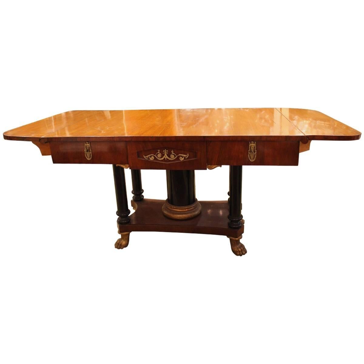 This elegant Biedermeier table is crafted from mahogany with gilt bronze decorative details, column legs, and claw feet. The drop sides accommodate your entertaining needs. Biedermeier gilt bronze-mounted and mahogany drop console table.
There are