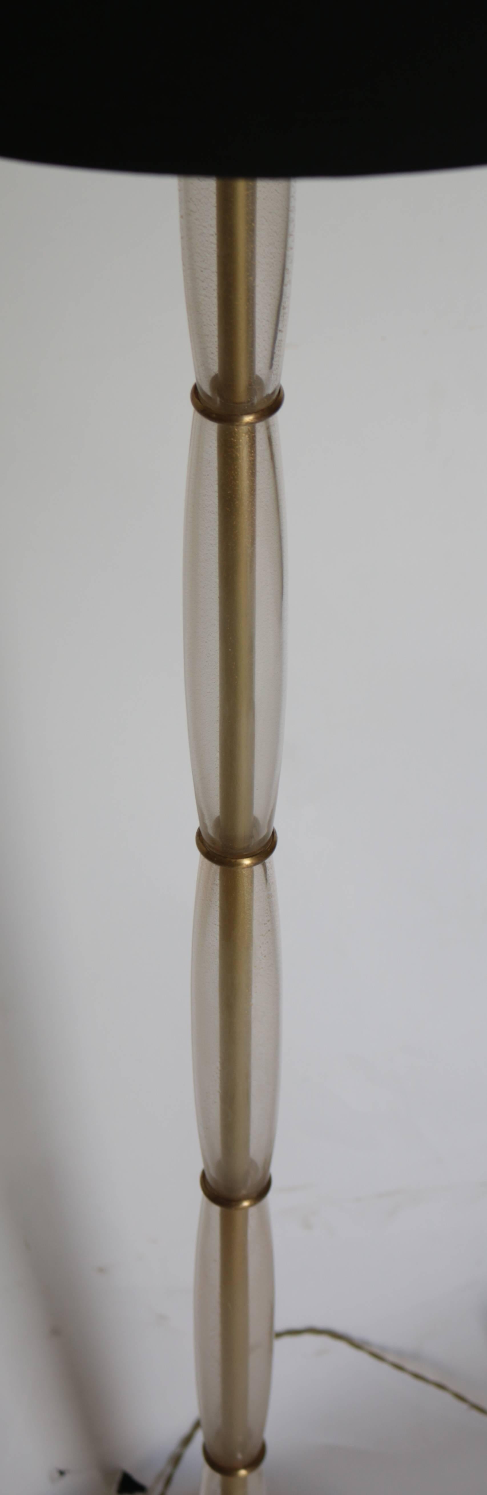 A beautiful modern Murano glass floor lamp by Donghia called the gigantic lamp in champagne with gold clusters. This piece is in excellent working condition and comes with a black linen shade that compliments the champagne beautifully. Decorated