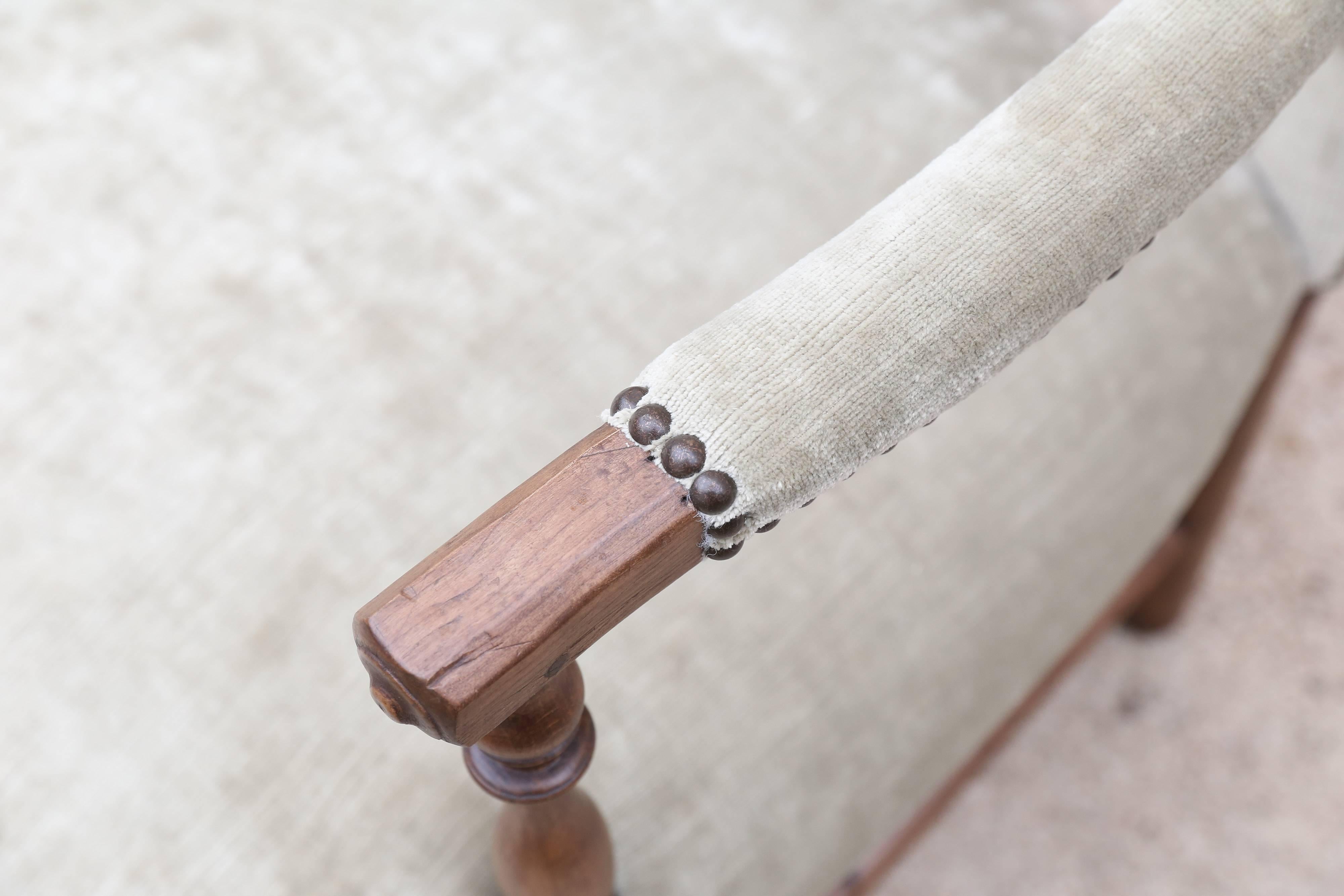 The open back and arms of this vintage French settee gives it a light and airy feel. Bowed bentwood stretchers, eight cylindrical legs and a slightly turned arm. Newly upholstered in a pale pistachio chenille with brass nailheads.