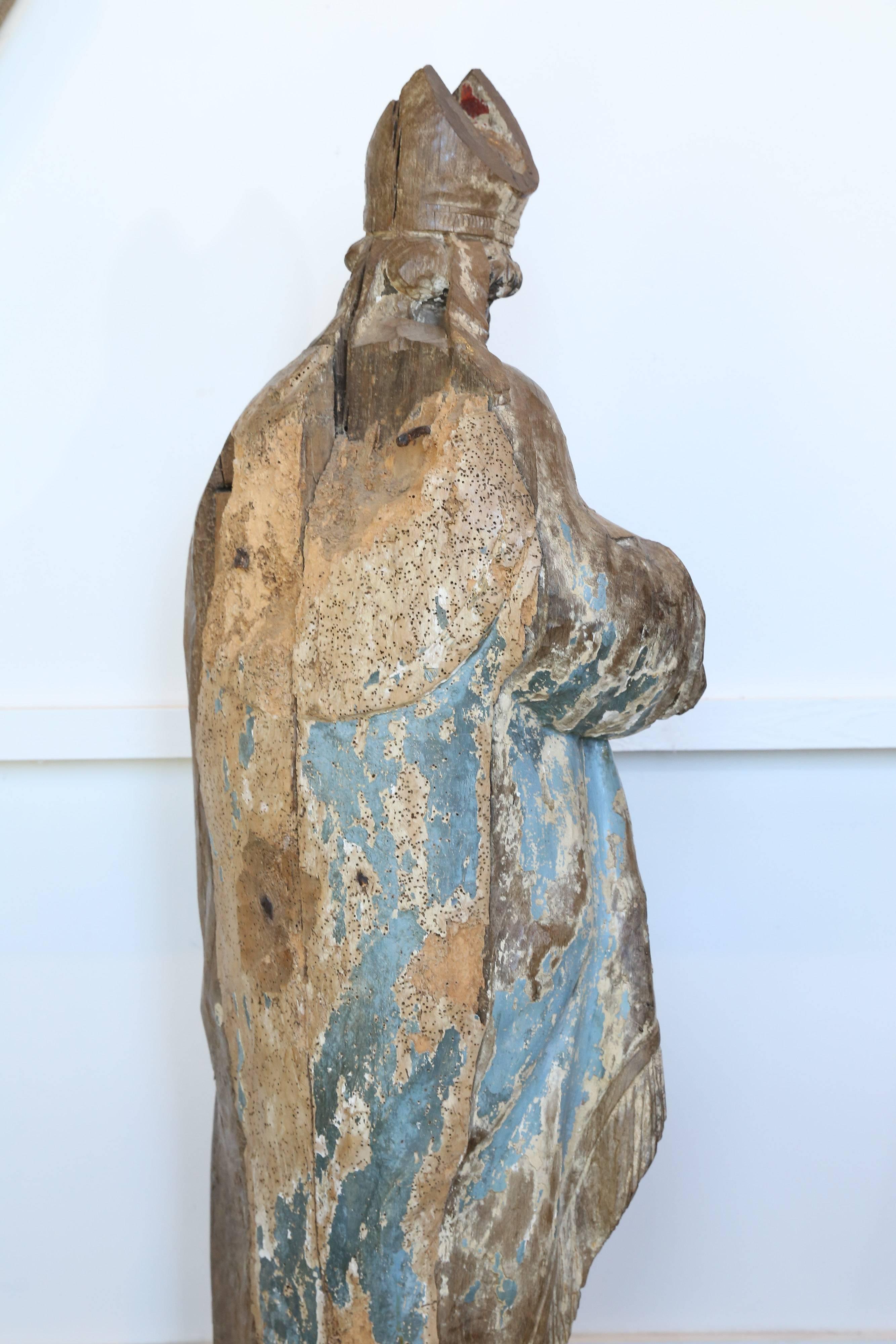 Carved from a solid piece of wood, this magnificent polychrome statue of a Catholic Cardinal is an exquisite example of the carver's art. Highly detailed and large in scale, the painted and gilded finish has been worn and dulled by age and there is