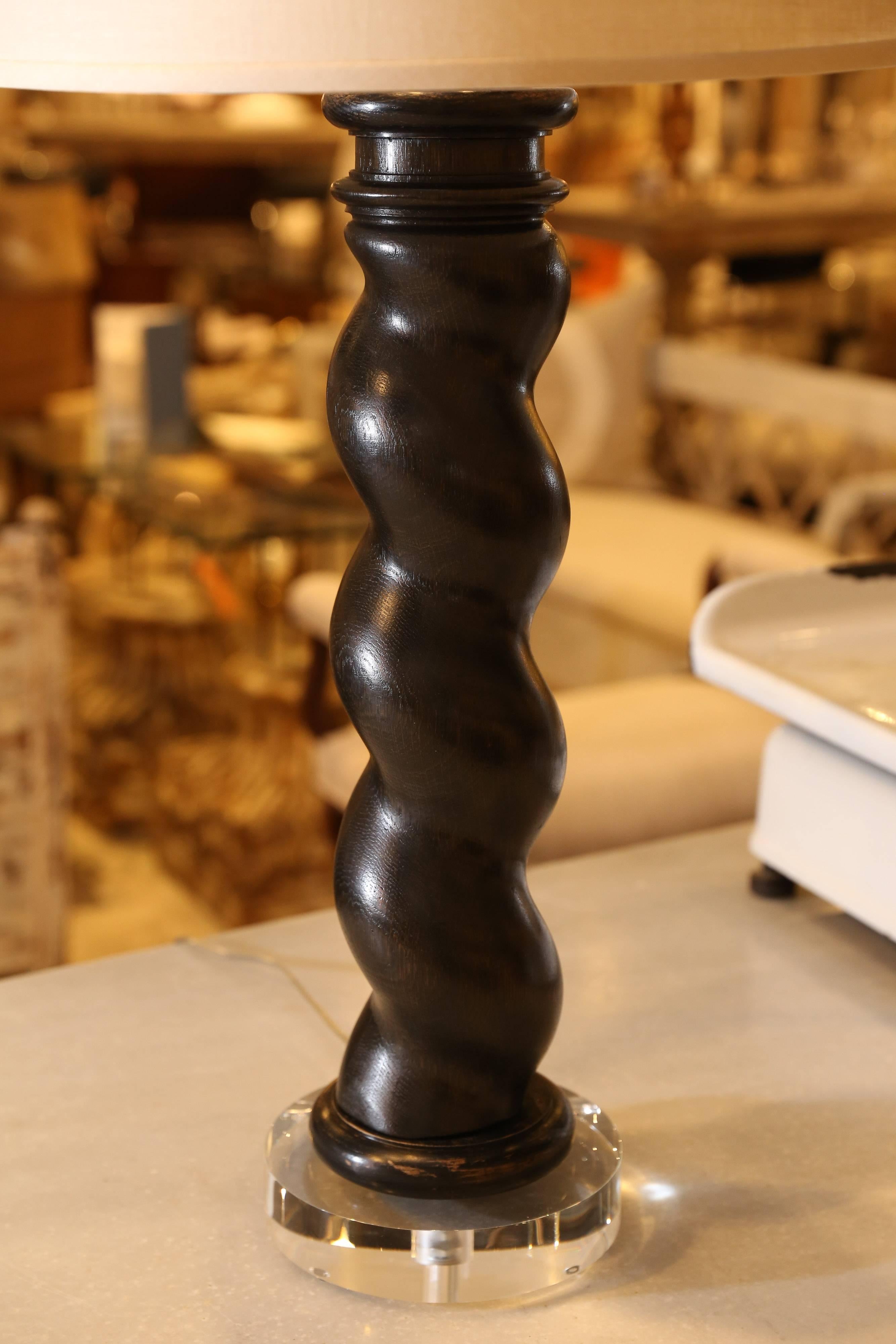 A marvelous old column from France reborn as an exceptional table lamp. The beautifully turned dark hardwood column has a tactile quality that almost insists that it be touched. Seated on an acrylic base with a 17 inch white shade, this makes a