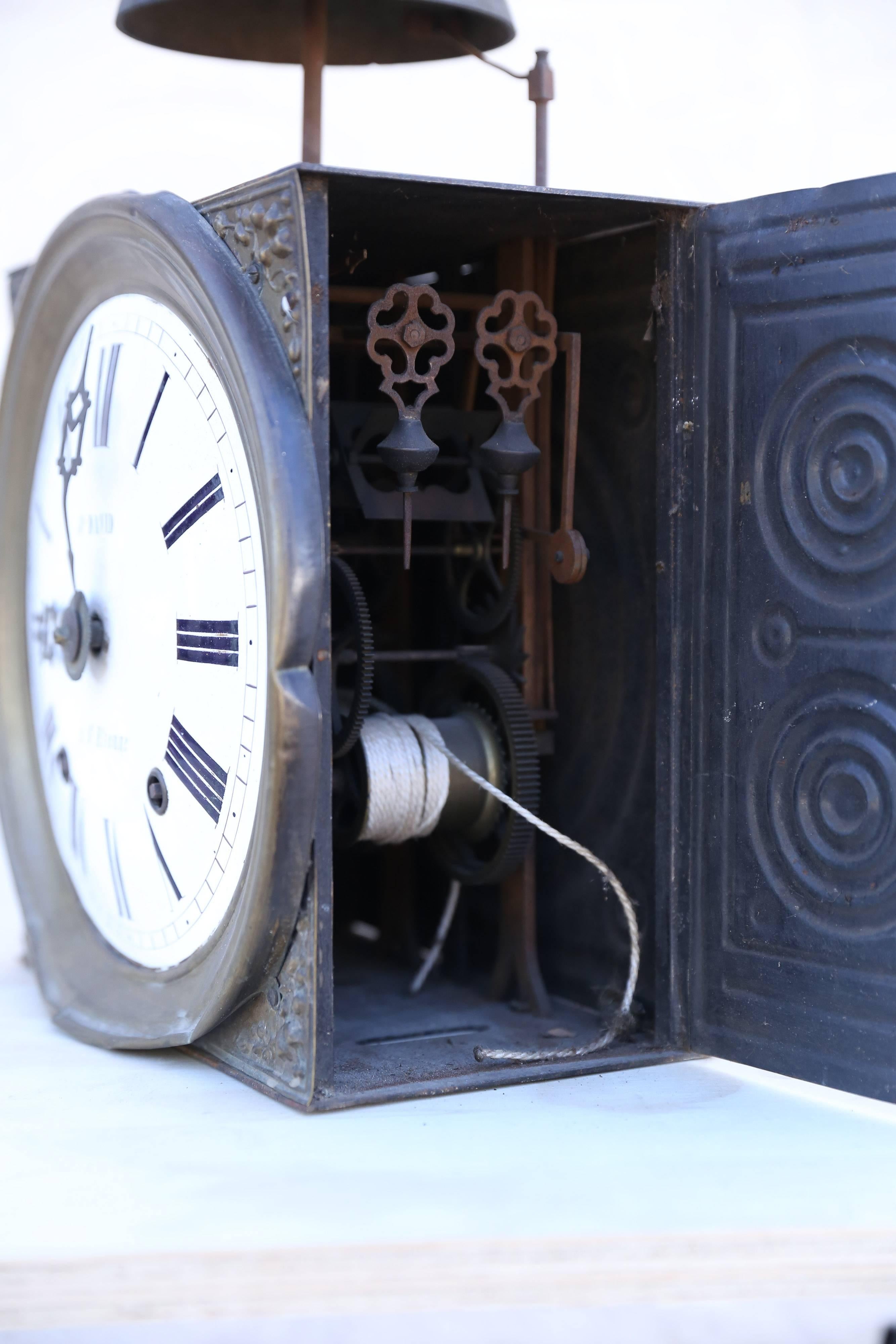 The face and inner workings of an old Grandfather's clock. Although it is no longer a working timepiece, time has not run out for this wonderful bit of yesteryear. Its proud face and ornate tin casing are topped by a splendid and imposing bell with