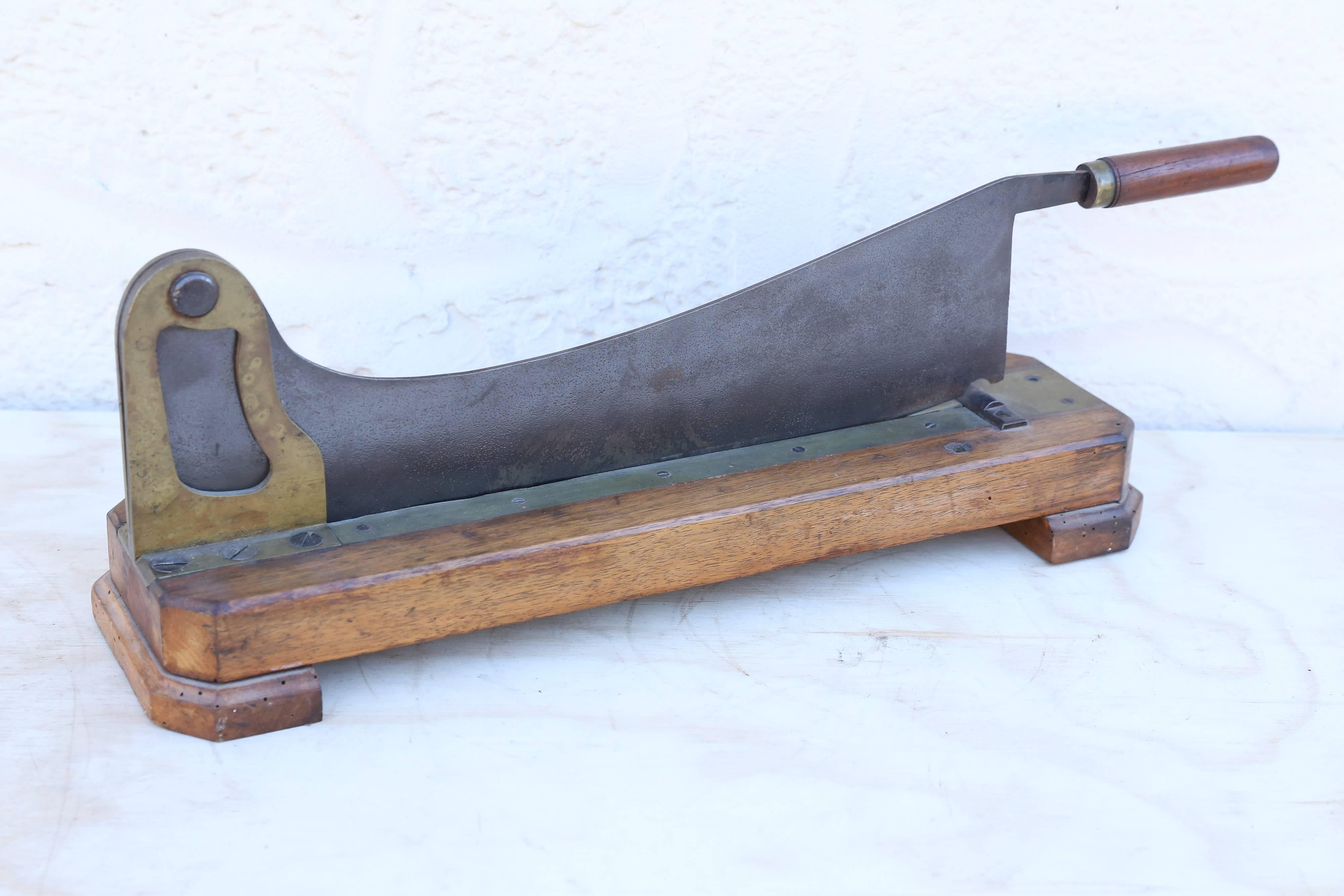A French bread and baguette guillotine, or slicer, on a wooden and brass base with a heavy steel hinged chopper.