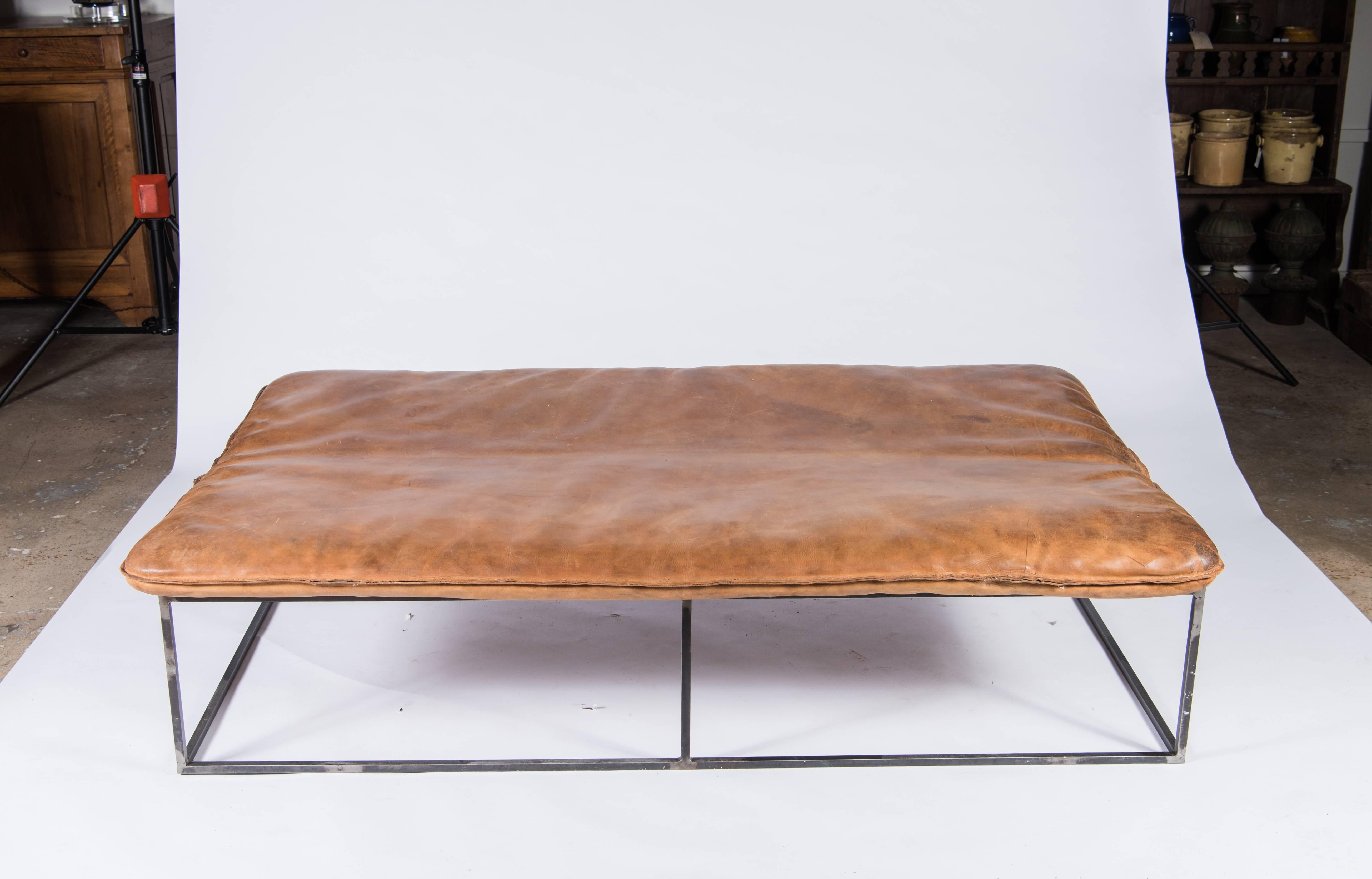 A beautifully aged leather gym mat from France on a Minimalist custom frame of blackened metal makes a clever and unique coffee table.