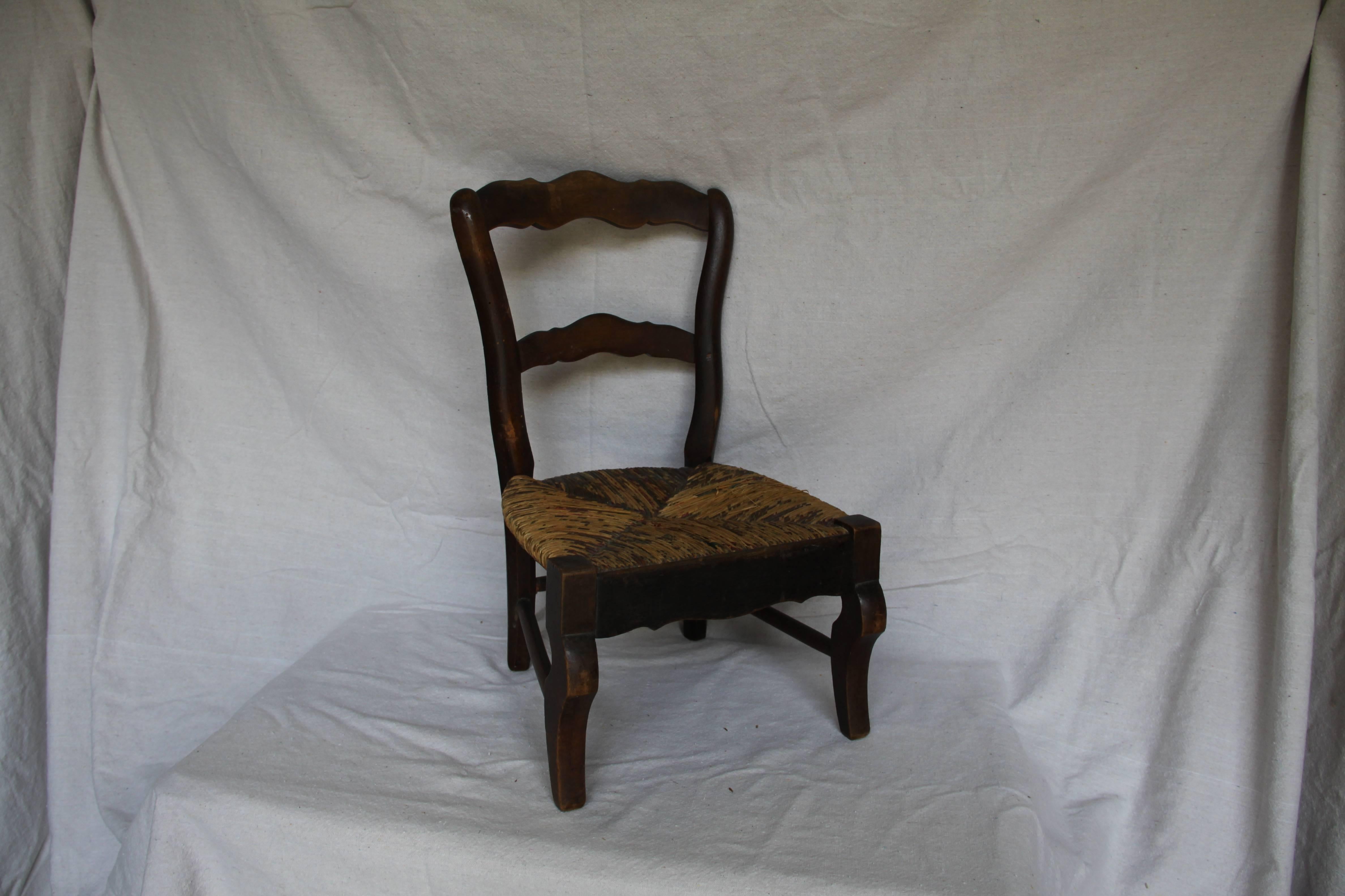 A truly wonderful child's side chair from France. Handmade from walnut with a rush seat, this would delight any child wanting his 'own chair' and would be charming just sitting alone beside the hearth. Solid in joint but with some breaking and loss