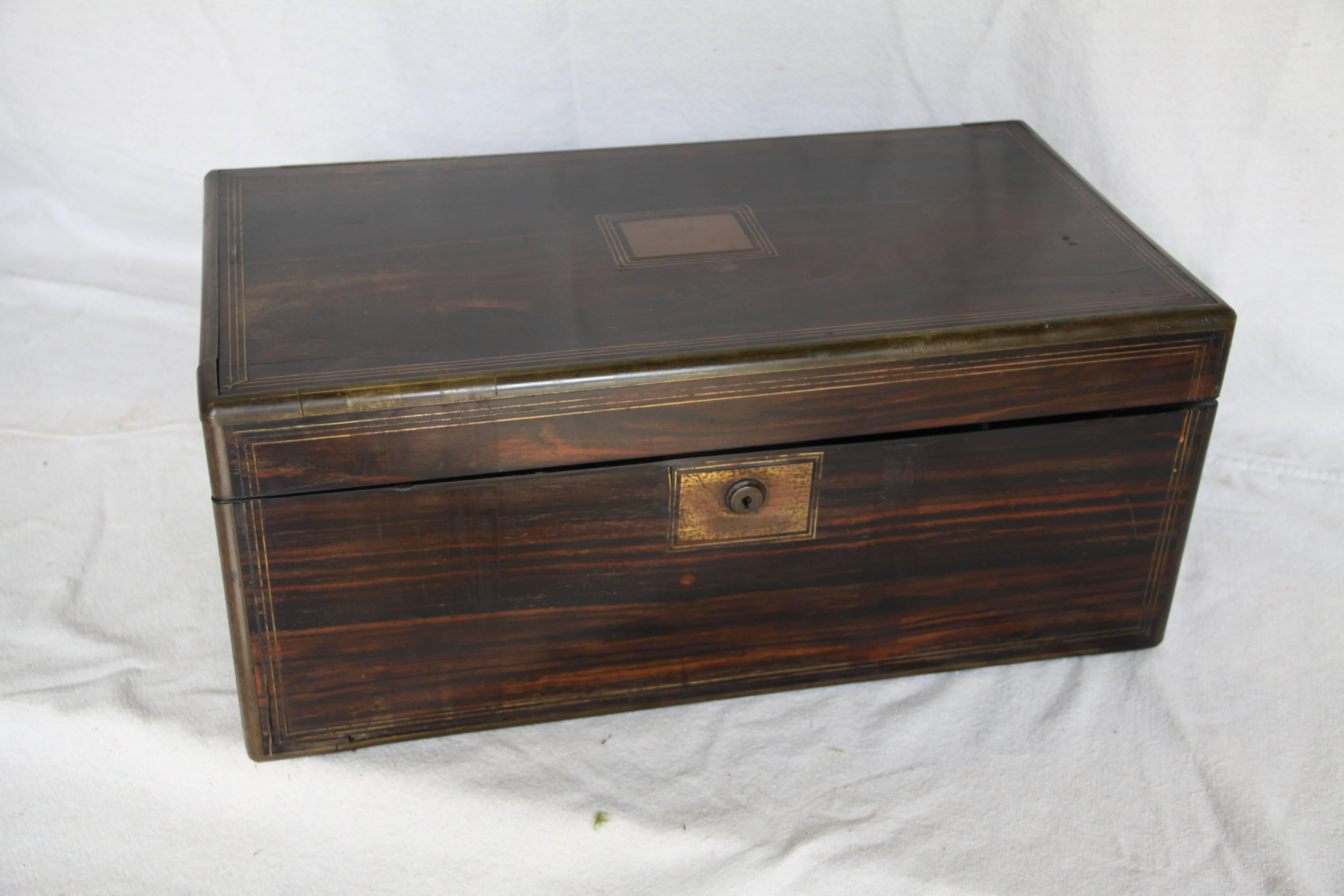 A large writing box with compartments found in France . Made of exotic wood with brass inlay banding, brass handles and escutcheon. A full-sized side drawer in the bottom is secured by a brass pin located in a slot in the interior. The surfaces of