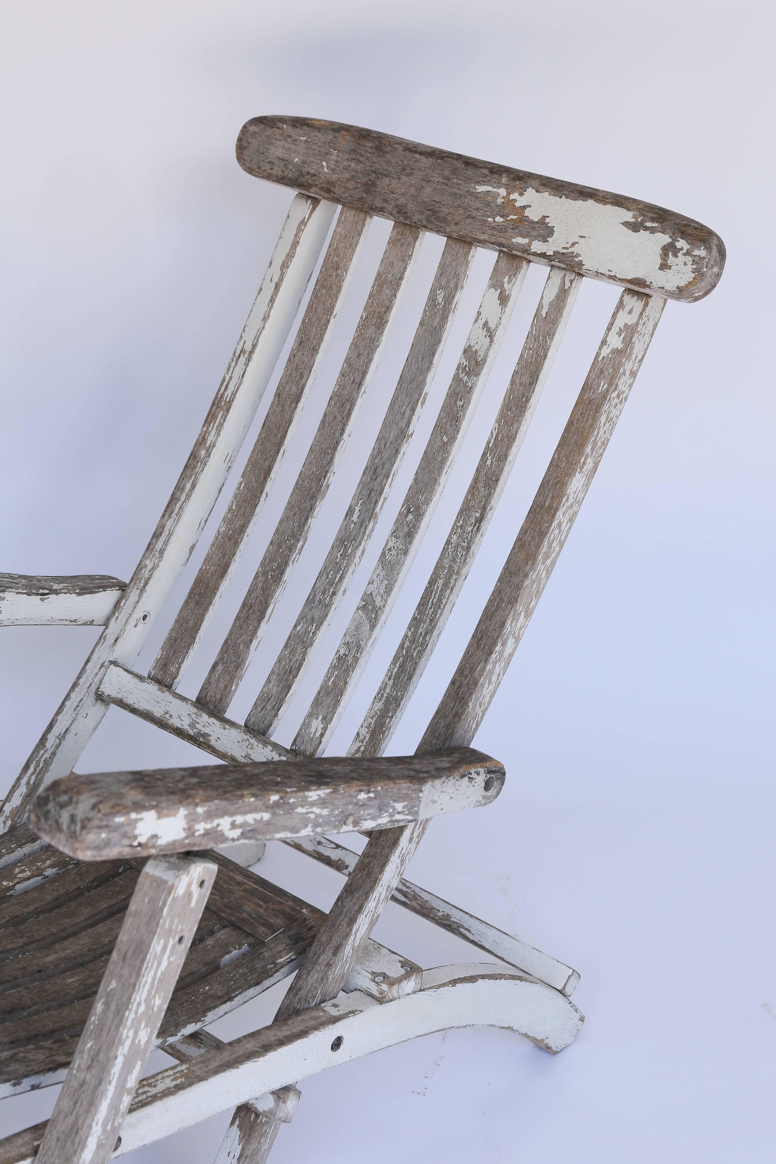 An iconic wood deck chair from France. Still strong and sturdy, traces of it's original white paint remain scattered over a surface that has primarily worn down to the original wood. Adjustable back and leg rest, the chair folds for easy storing.