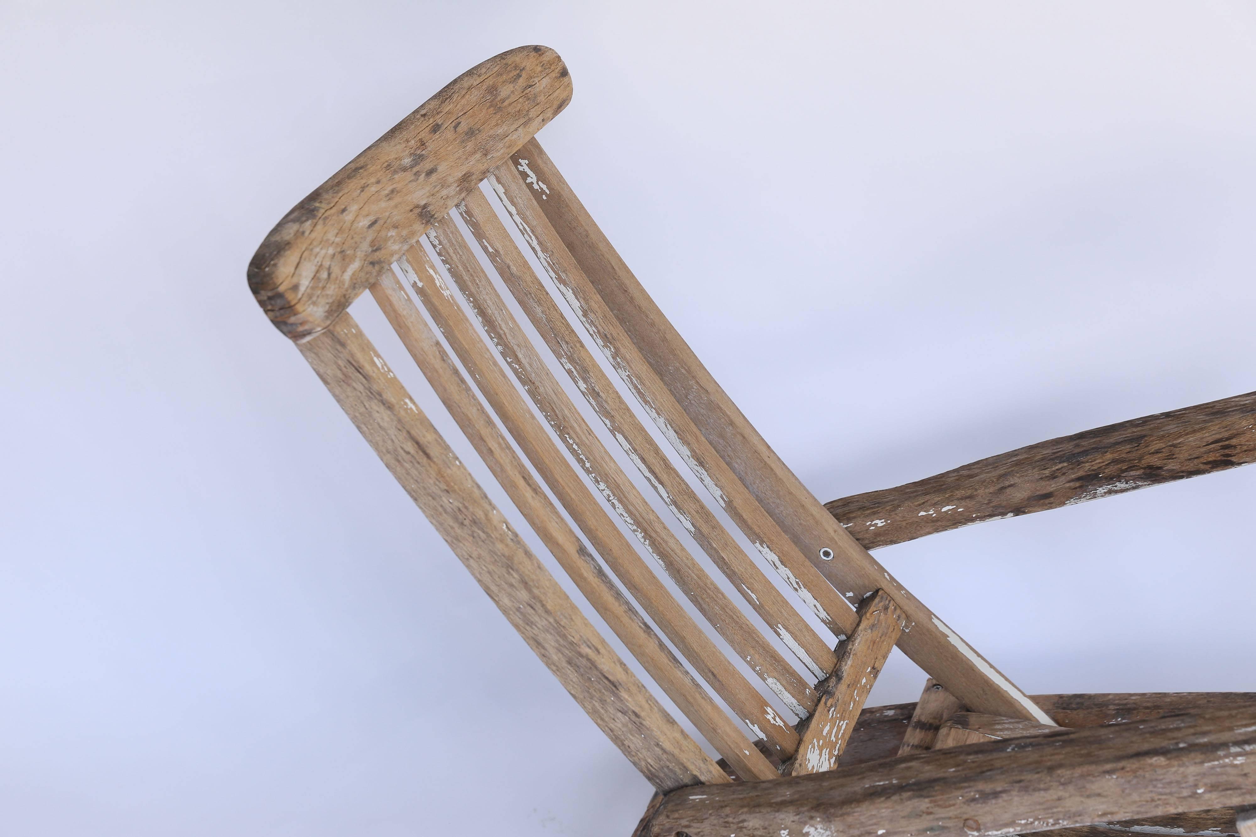 An iconic wood deck chair from France. Still strong and sturdy, traces of it's original white paint remain scattered over a surface that has primarily worn down to the original wood. Adjustable back and leg rest, the chair folds for easy storing.