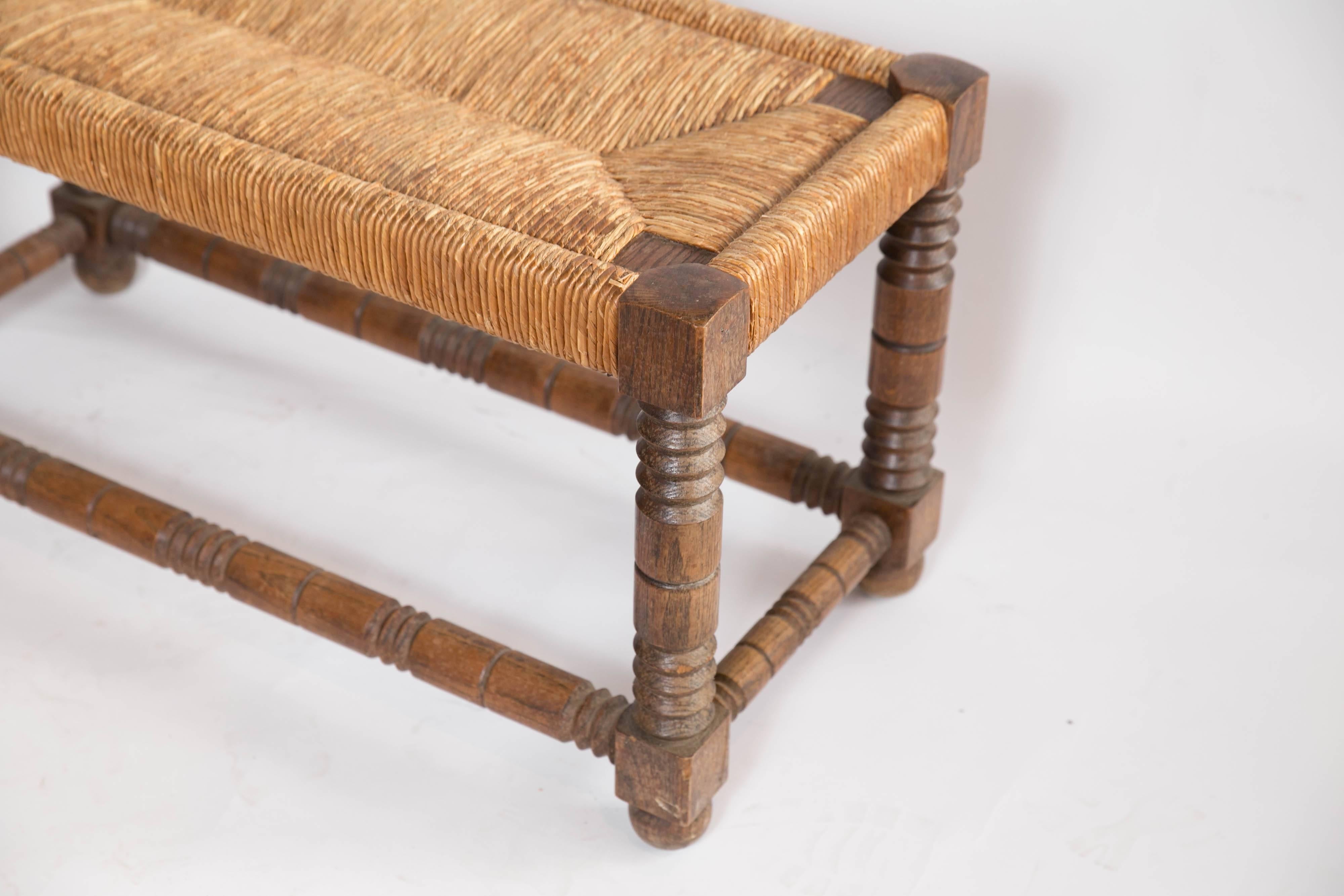 With a nod towards Jacobean styling, a striking rush seat bench from France. Heavy and solid with beautifully turned legs and stretcher bars supporting a rush seat in immaculate condition.