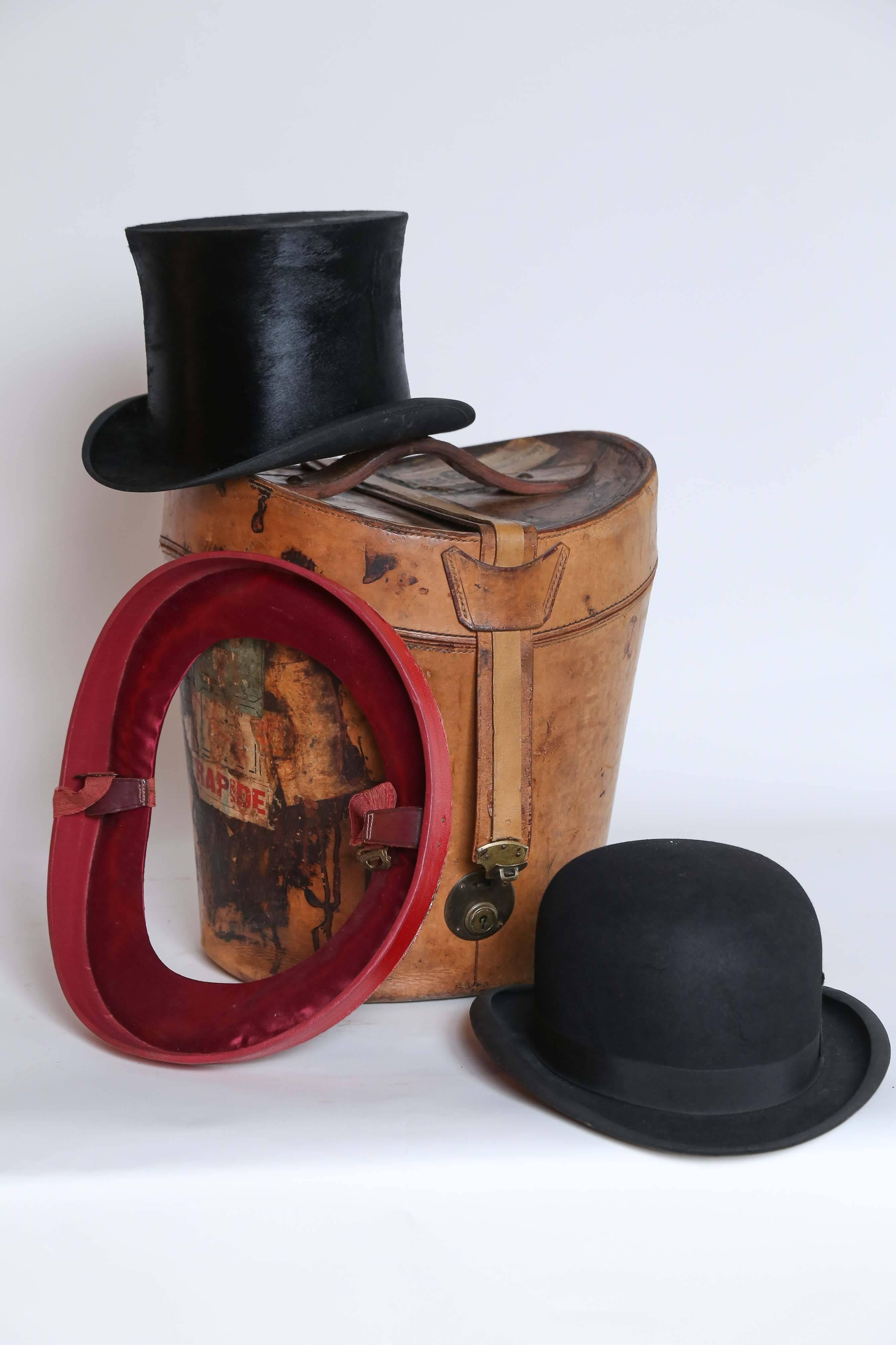 From France, a leather hat box containing a top hat and a bowler. The Top Hat is marked Renard Leriche, Paris, 1900 and is in wonderful condition. The bowler is newer and marked Madelios, Paris but it does have a crack in the crown. The box, lined