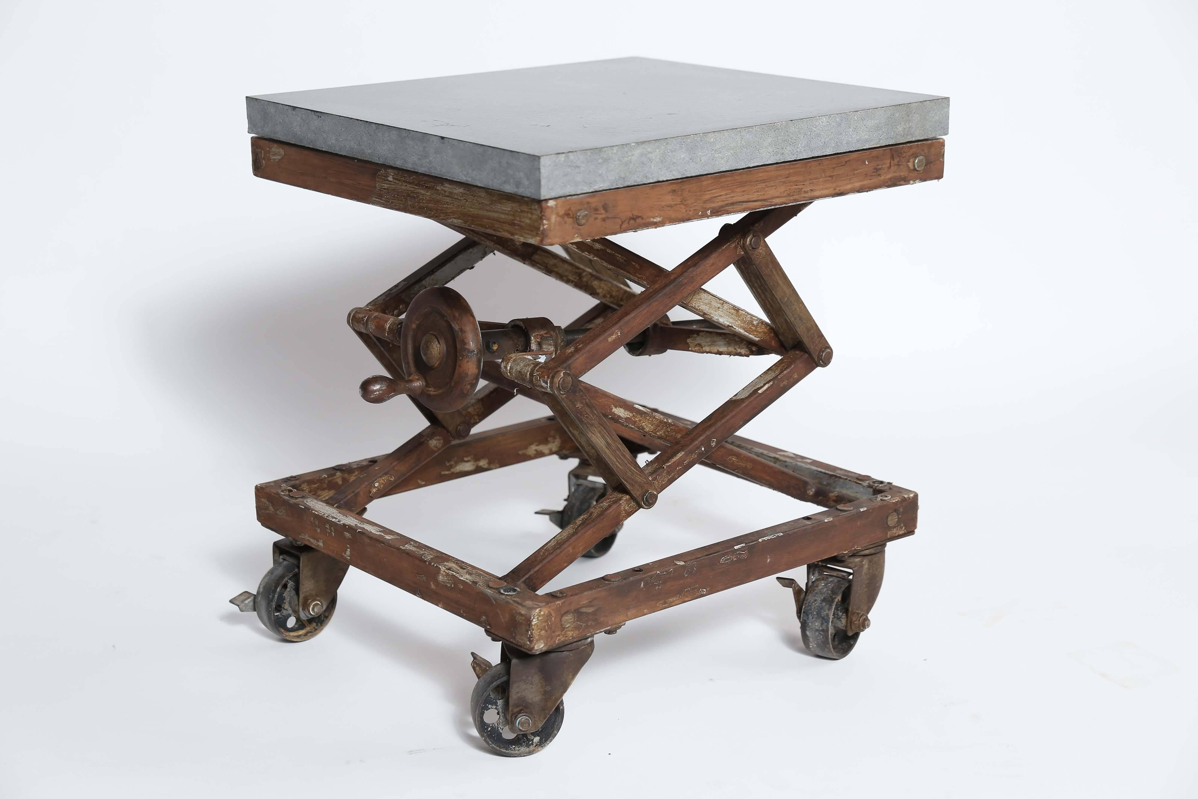 A vintage scissor lift becomes a side table or a high/low stool. Made of iron with a stone top, it's height ranges from 12 inches to 26 inches making it as versatile as it is cool. With locking wheels and a side crank. Two available.