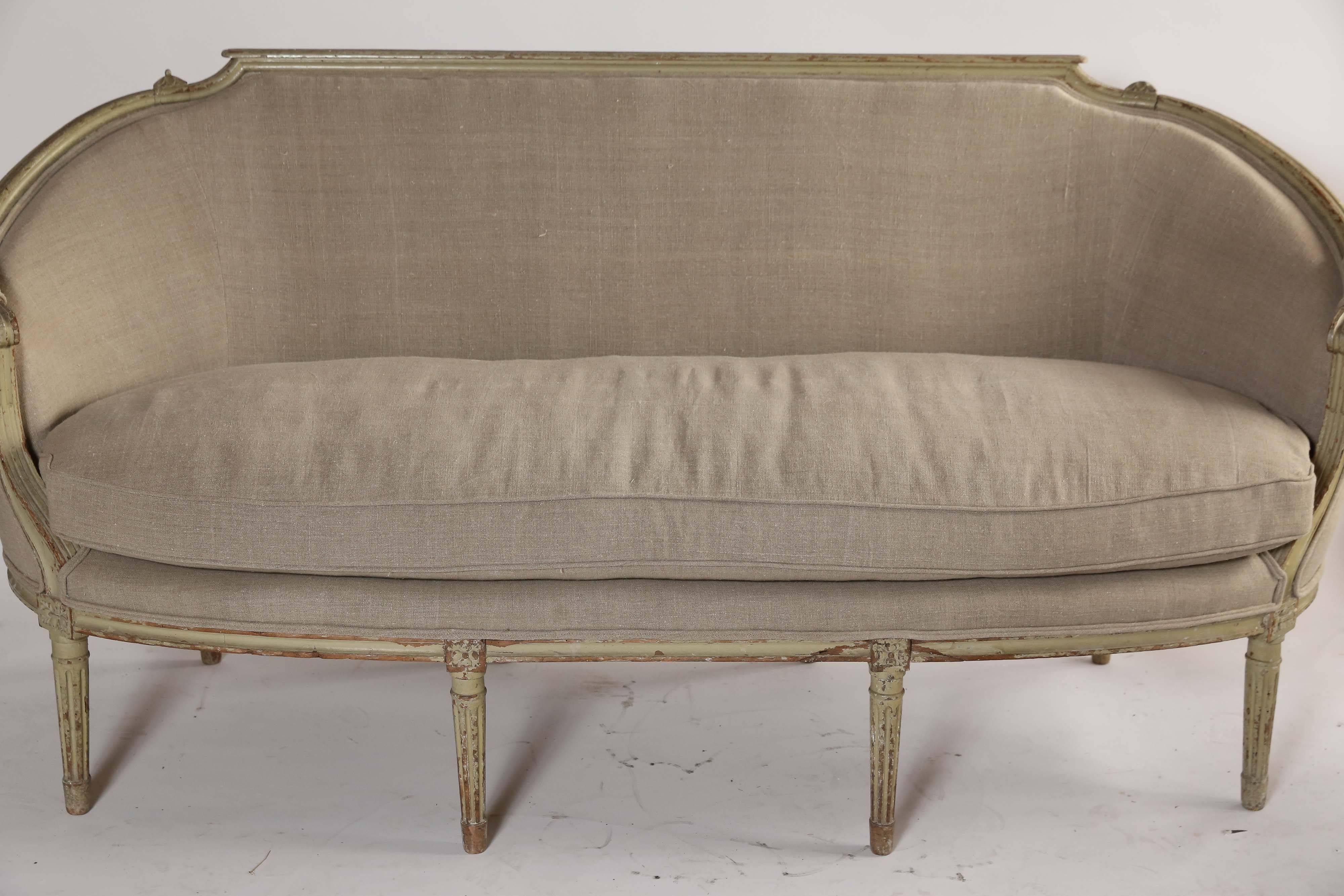 Graceful curved lines on a Classic French settee. With traces of it's original pale green paint and newly upholstered in linen, this delightful piece has double cord welting on the frame and a new down-filled cushion. Light and elegant.