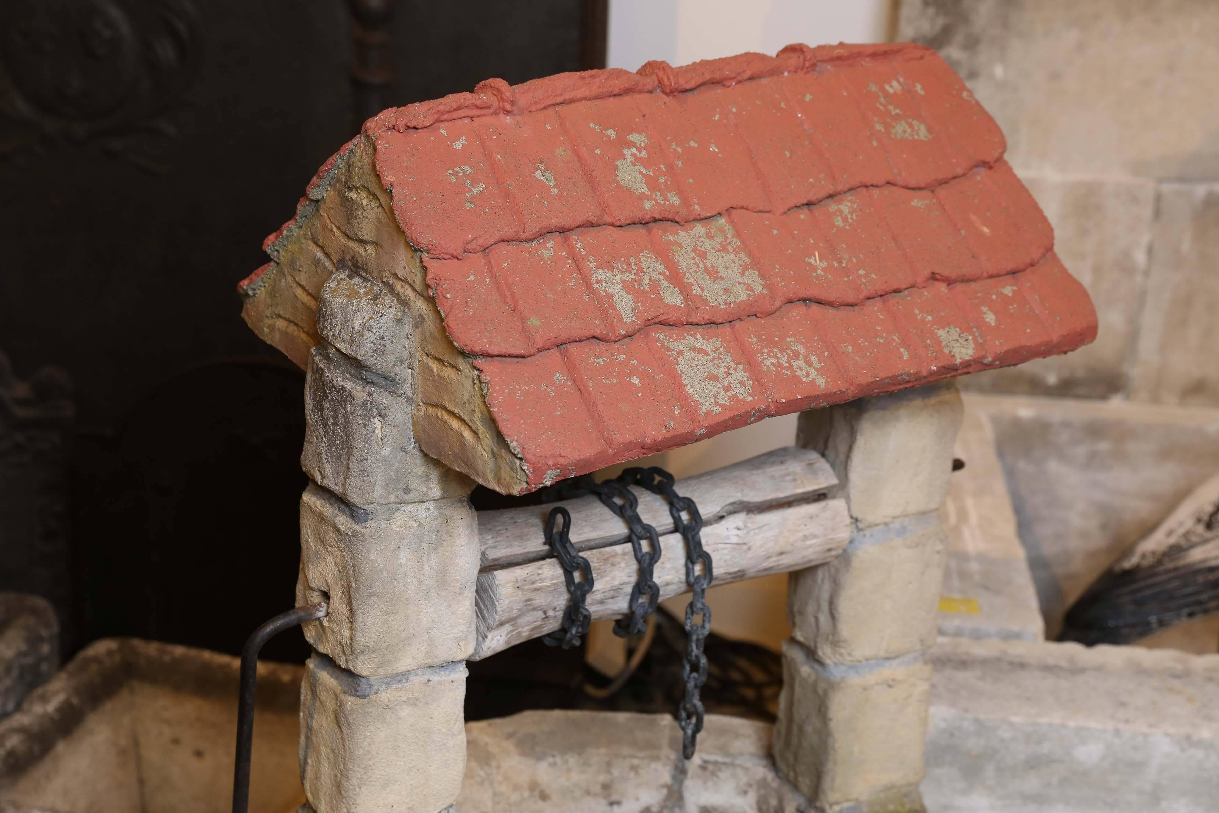 A charming concrete wishing well from France. A metal hand crank turns a wooden spindle with a chain attached for a bucket. The roof has worn terracotta paint. Add some magic to a shady spot in the garden.