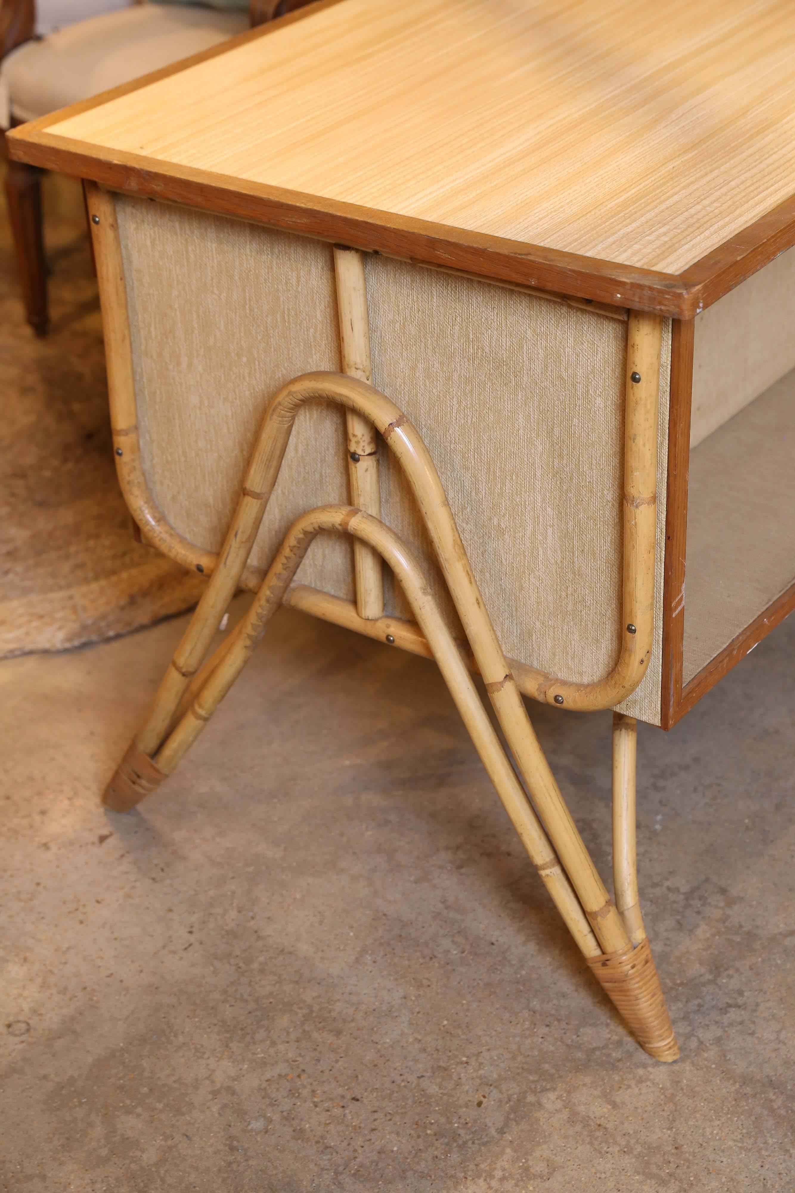 Un petit et charmant bureau et une chaise en bambou à trois tiroirs provenant de France. Le bureau est construit en bois et en panneaux de fibres avec des pieds et des garnitures en bambou. Le plateau est en stratifié grain de bois garni de bois,