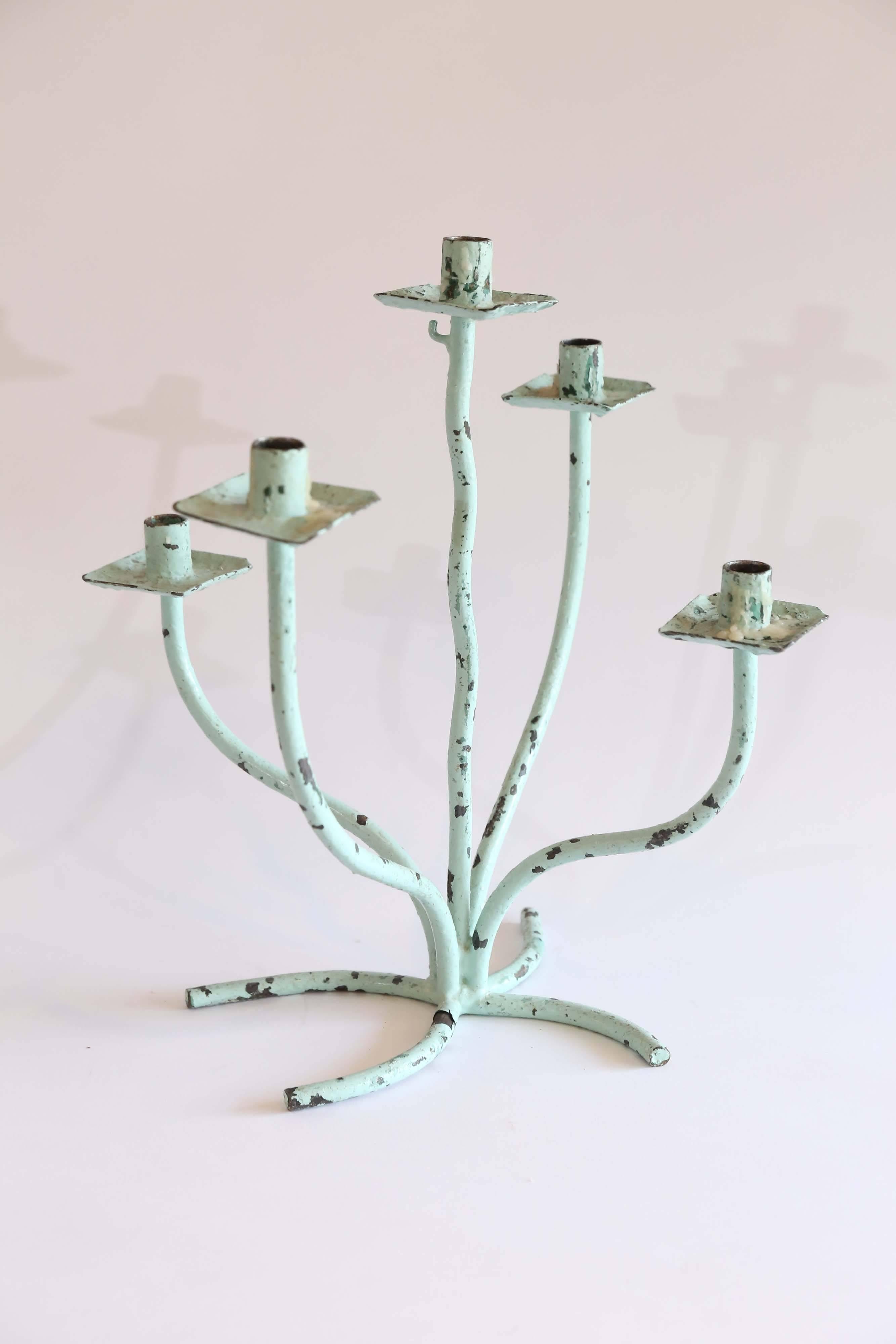 A pair of eccentric wrought iron candelabra from France. With chippy old seafoam green paint, the five free-form arms extend up from a four pronged base. Quirky and fun, there are two others available and sold separately- one seafoam green and one
