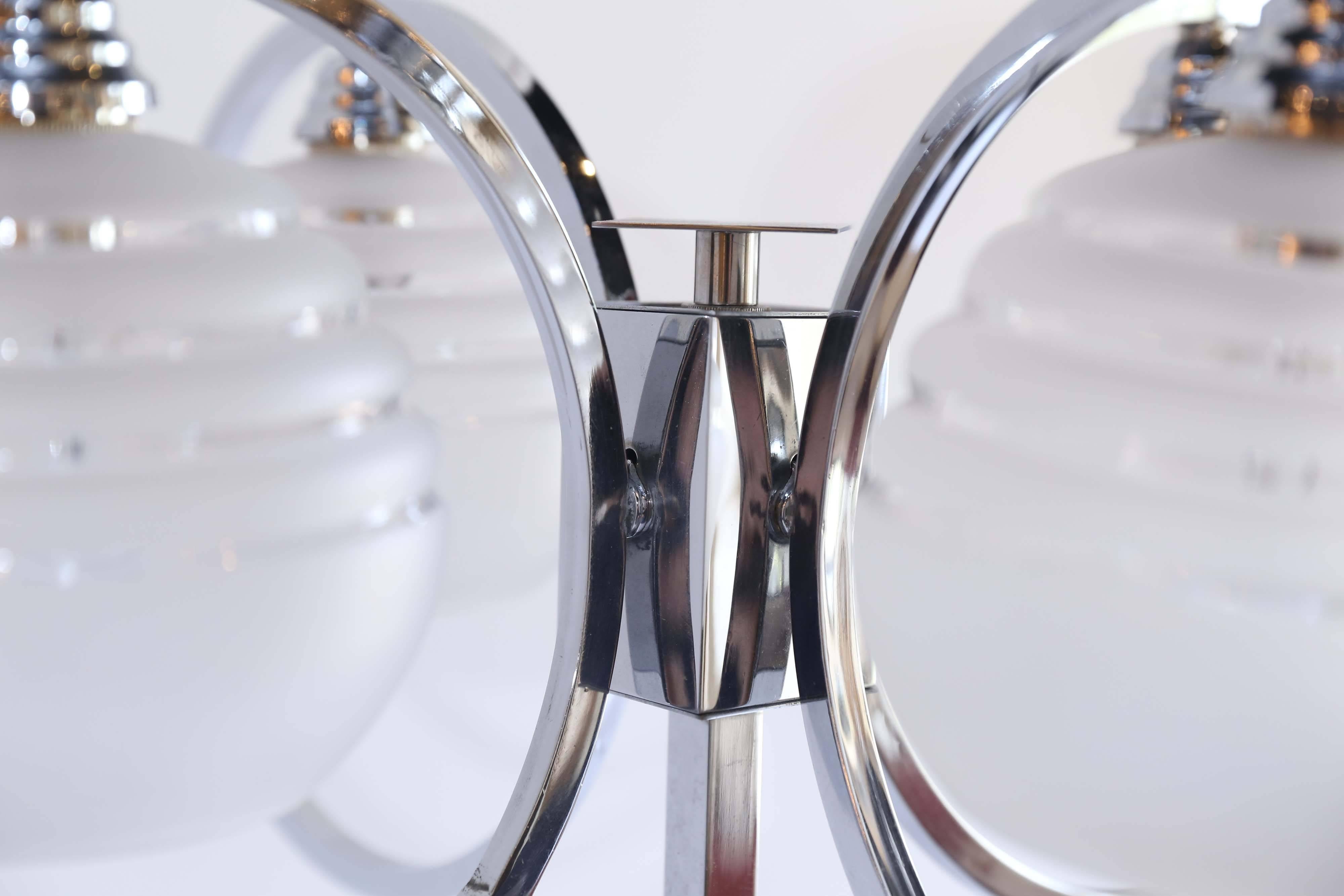 An up-purposed chrome four-light midcentury table lamp from France. Once a chandelier, the piece has been flipped and fitted onto an acrylic base. Four shaped globes of frosted glass with clear glass accents are suspended inside chrome circles.